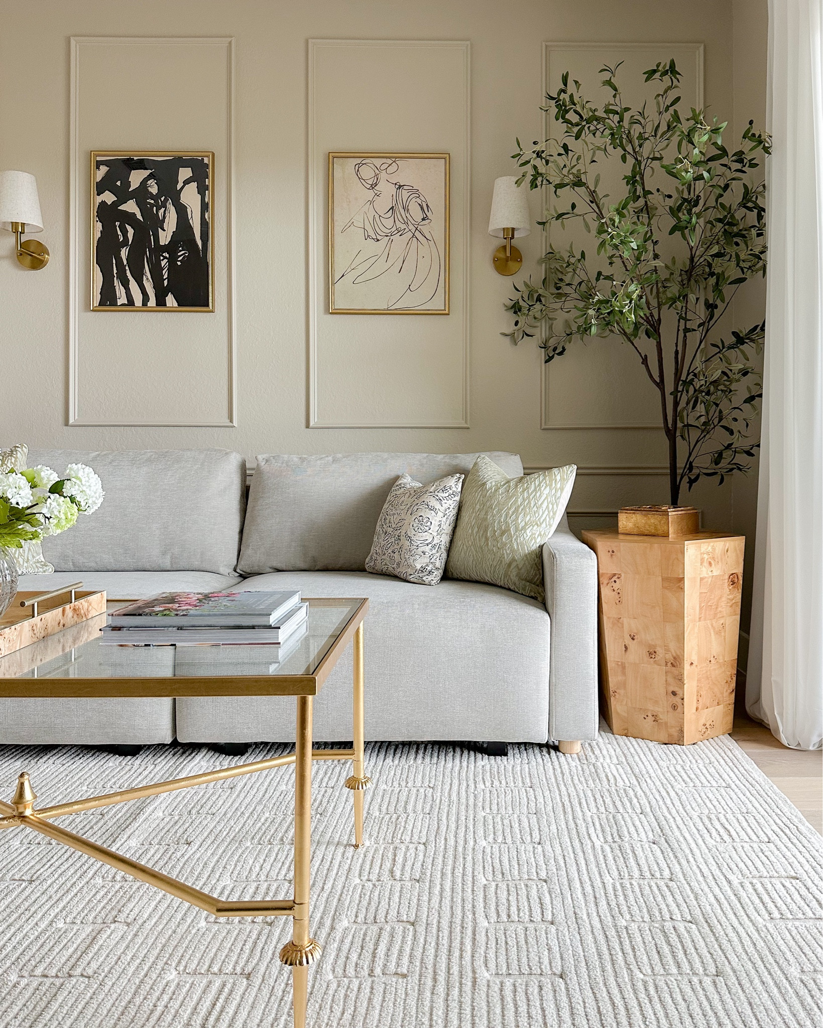 Lounge room corner including this super realistic delicate olive tree, Burl wood table, neutral sofa, abstract modern bold artwork, wireless sconces, pillow covers, and gold coffee table!

#LTKsalealert #LTKhome #LTKfindsunder50
