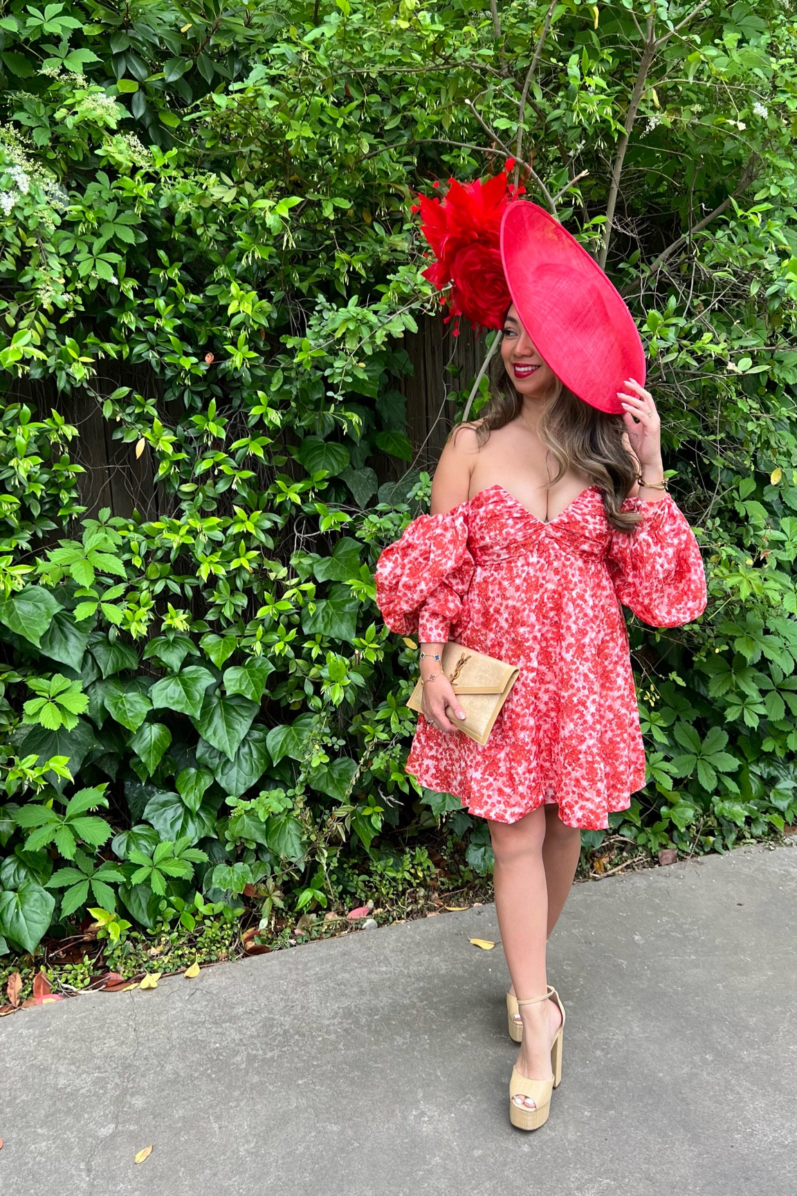 Melllypoo is wearing a red rose fascintor hat with a strapless off the shoulder puff sleeve floral dress with raffia platform heels and a ysl raffia clutch and gold jewelry for a Kentucky Derby party  

#LTKSeasonal #LTKWedding #LTKParties
