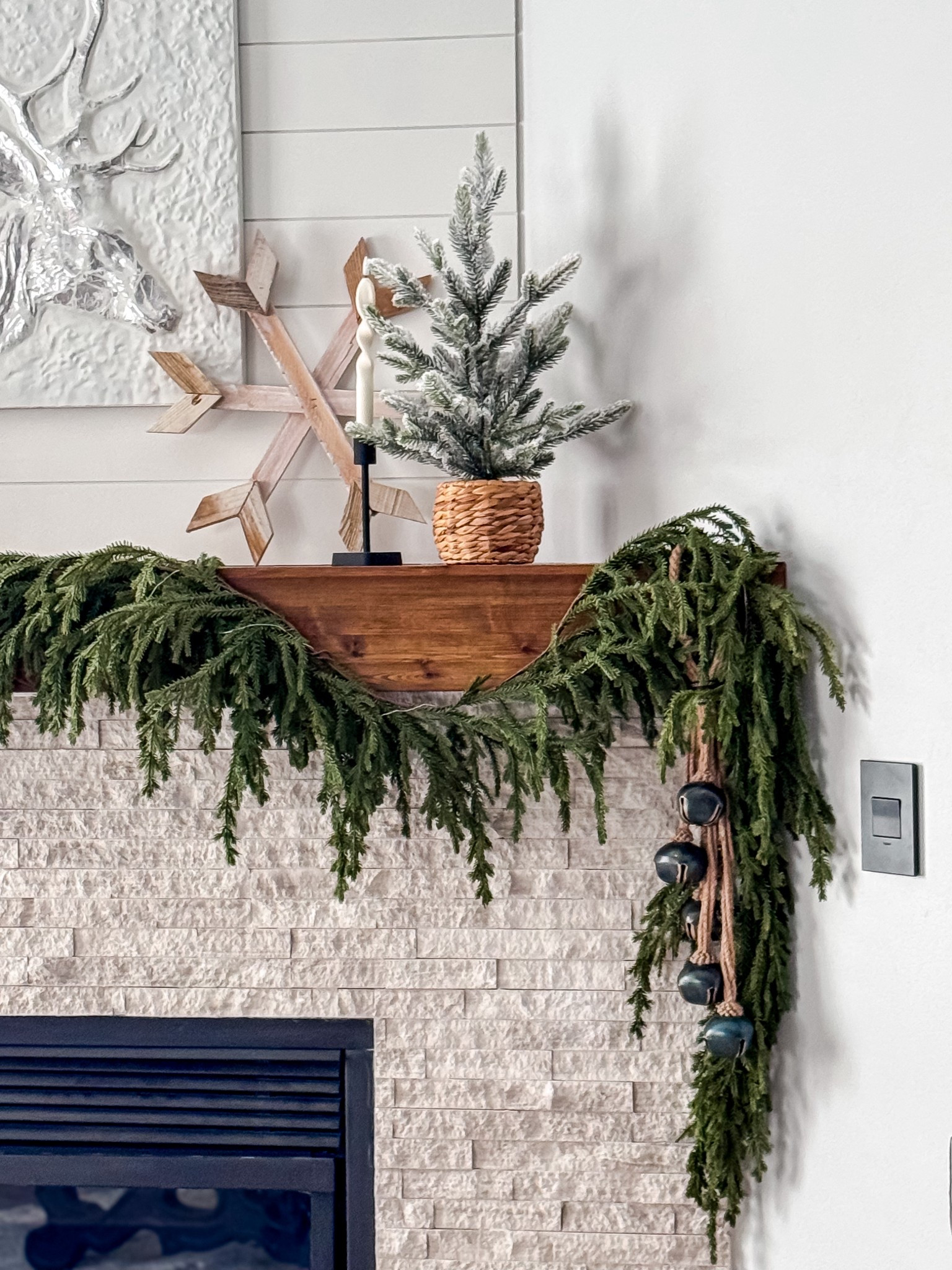 Re-Create this mantle look with in stock items.
This cozy, modern farmhouse mantle look is all about simple textures, soft winter greens, and warm wood tones. I started with a lush faux cedar/evergreen garland and let it drape naturally for that effortless, organic shape. On one side, I added a rustic bell garland for subtle movement and charm.

For the top of the mantle, keep it minimal and balanced: a mini flocked pine tree in a woven basket planter adds that wintery touch without overpowering the space, and a set of neutral taper candles on a black holder brings height and warmth. To finish, lean a wooden snowflake or winter wall accent against a textured art piece or mirror for that layered, designer look.

This setup works perfectly for Christmas and can easily stay up all winter just by switching out a few seasonal accents.

Mantle Decor • Christmas Mantle • Winter Mantle • Holiday Decor Inspo • Farmhouse Christmas • Modern Farmhouse Style • Neutral Christmas • Cozy Home Decor • Festive Home • Holiday Styling • Christmas Vibes • Neutral Home • Rustic Christmas • Winter Decor Ideas • Simple Holiday Decor • Minimal Holiday • Living Room Decor • Cozy Living • Decor Inspiration • Holiday Home Finds • Christmas Aesthetic 

#LTKHoliday #LTKHome #LTKSeasonal