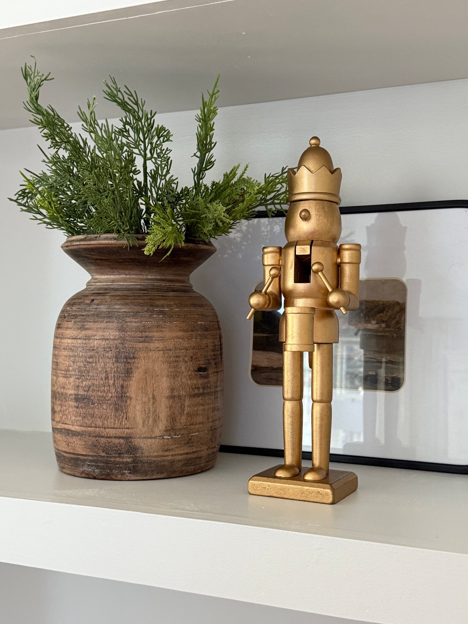 I love the subtle touch of gold this nutcracker adds to the shelf, layered with art, holiday greenery, and wood accents.

#LTKSeasonal #LTKHome #LTKHoliday