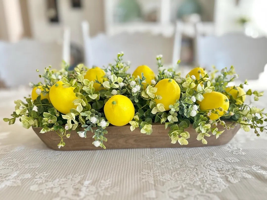 Bright, fresh, and full of sunshine—this lemon and greenery centerpiece is the perfect way to bring a cheerful summer vibe into your home. Styled in a rustic wooden dough bowl, it features vibrant faux lemons paired with lush greenery and soft white florals for a look that feels both crisp and inviting. Whether placed on a kitchen island, dining table, or entryway, this handcrafted piece instantly adds a pop of color and farmhouse charm that lasts all season long. #LTKhome #summerdecor #farmhousestyle #kitchendecor #tabledecor #lemondecor #cozyhome #seasonalstyle

#LTKHome #LTKWedding #LTKSeasonal