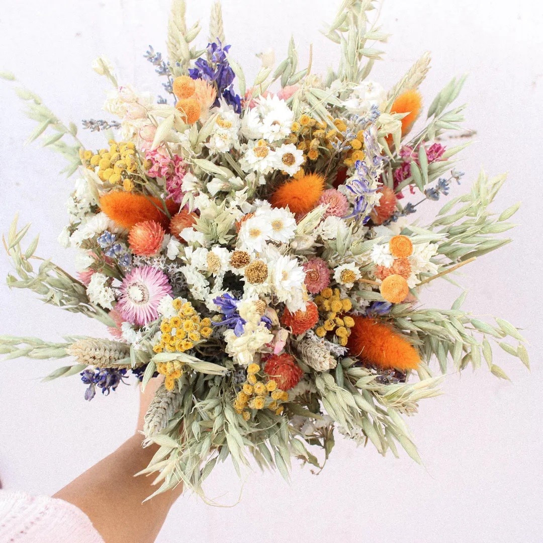 Warm, whimsical, and full of meadow charm—the Orange Dream Dried Flower Bouquet by Bridalwishdesign is a stunning blend of texture and color. Designed with vibrant strawflowers, soft bunny tails, light green oats, pink globe amaranth, purple-blue larkspur, preserved daisies, and natural grasses, it brings together sunset oranges, lavender tones, and soft neutrals for a truly eye-catching arrangement. Perfect for fall weddings, Thanksgiving décor, or adding a wildflower touch to your celebration, this one-of-a-kind bouquet is available in four sizes and made to be treasured long after the day is done. 🍂💐 #LTKwedding #FallWedding #DriedFlowerBouquet #WildflowerStyle #BohoBride #ThanksgivingDecor #EverlastingBlooms

#LTKSeasonal #LTKWedding #LTKHome