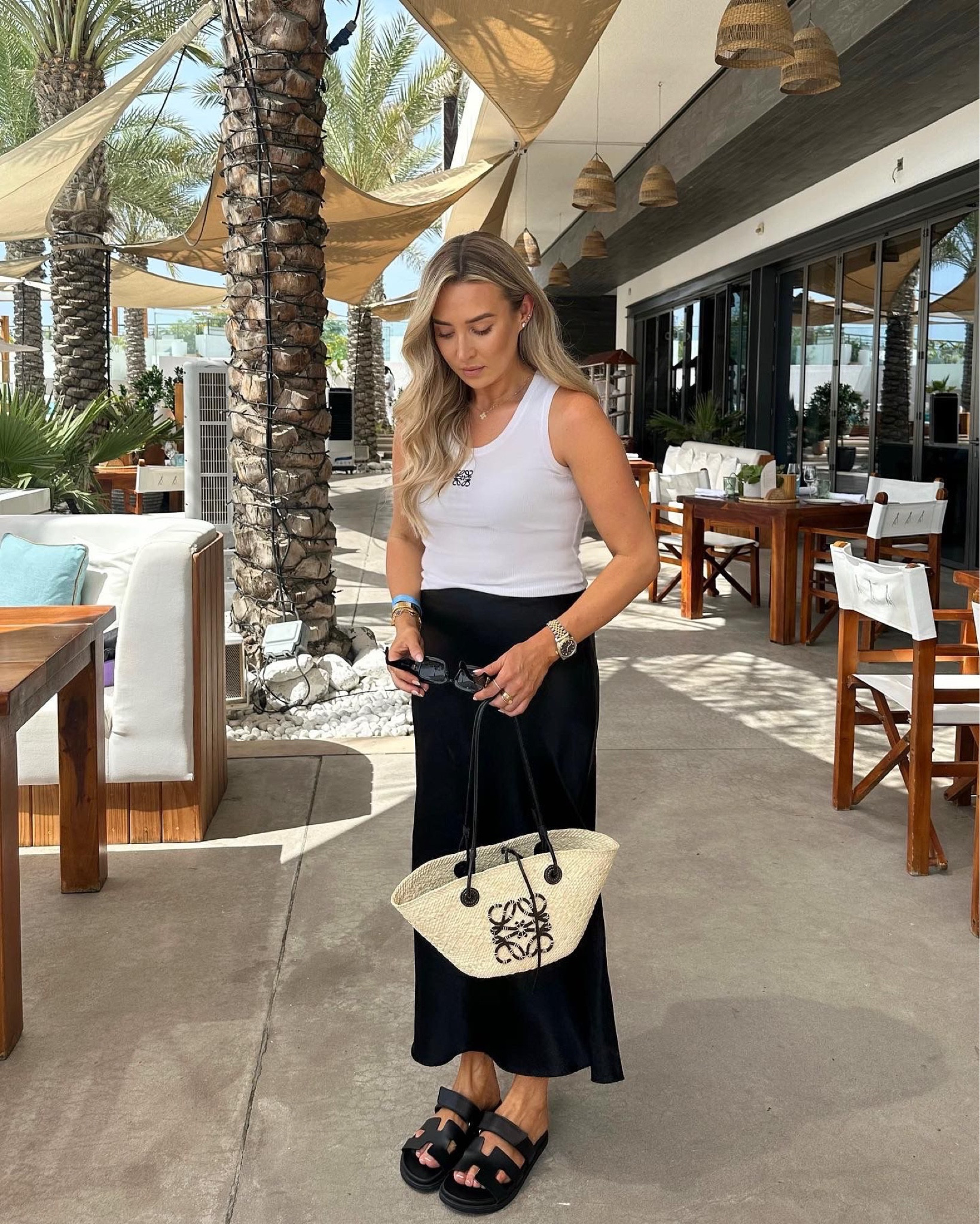 Simple summer look from my Dubai trip - arket black satin skirt, white Loewe anagram vest top, black sunglasses & basket bag, styled with the Hermes Chypre sandals

#LTKstyletip #LTKeurope #LTKSeasonal