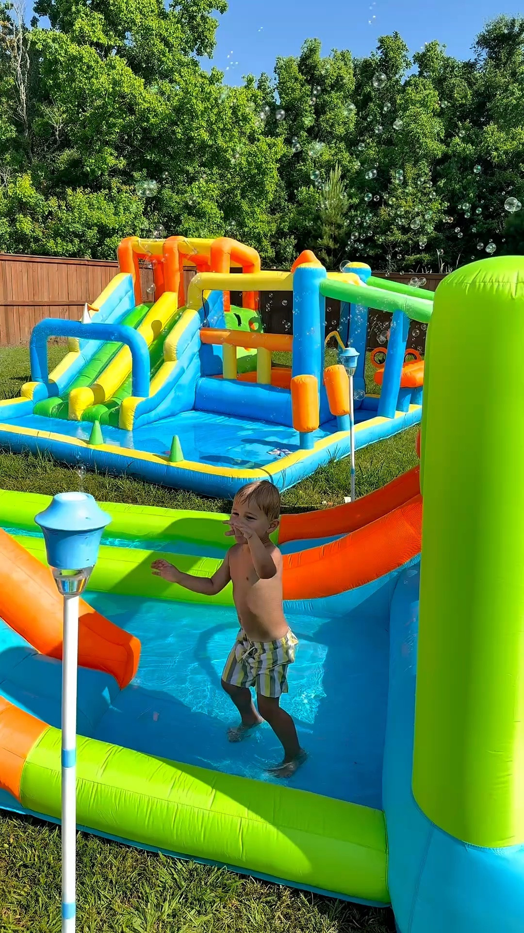 Summer bounce house, bubble machine and snack tray set up #waterslide #summer #bouncehouse #LTKFamily