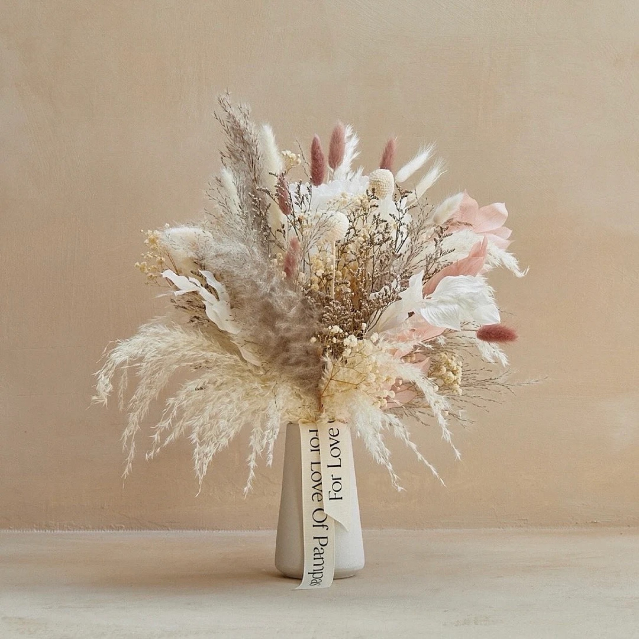 Soft, romantic, and effortlessly elegant—the “Mica” dried bouquet blends pampas grass, billy balls, ruscus, bunny tails, preserved hydrangea, baby’s breath, and limonium in a calming mix of ivory, natural tones, and a hint of blush pink. Its airy texture and subtle color palette make it the perfect accent for any room, adding warmth without overwhelming your space. Designed to last for over a year with no maintenance, it’s a timeless piece for everyday styling or a thoughtful, long-lasting gift. #ltkhome #ltkdecor #driedflowers #neutraldecor #bohodecor #pampasgrass #homestyling #cozyhome #everlastingflowers

#LTKSeasonal #LTKHome #LTKWedding