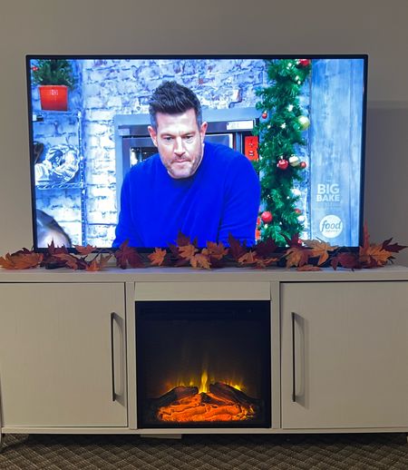 Holiday Baking Championship looks better on a Fire TV, over a fake fire. TV stand from Wayfair but similar linked