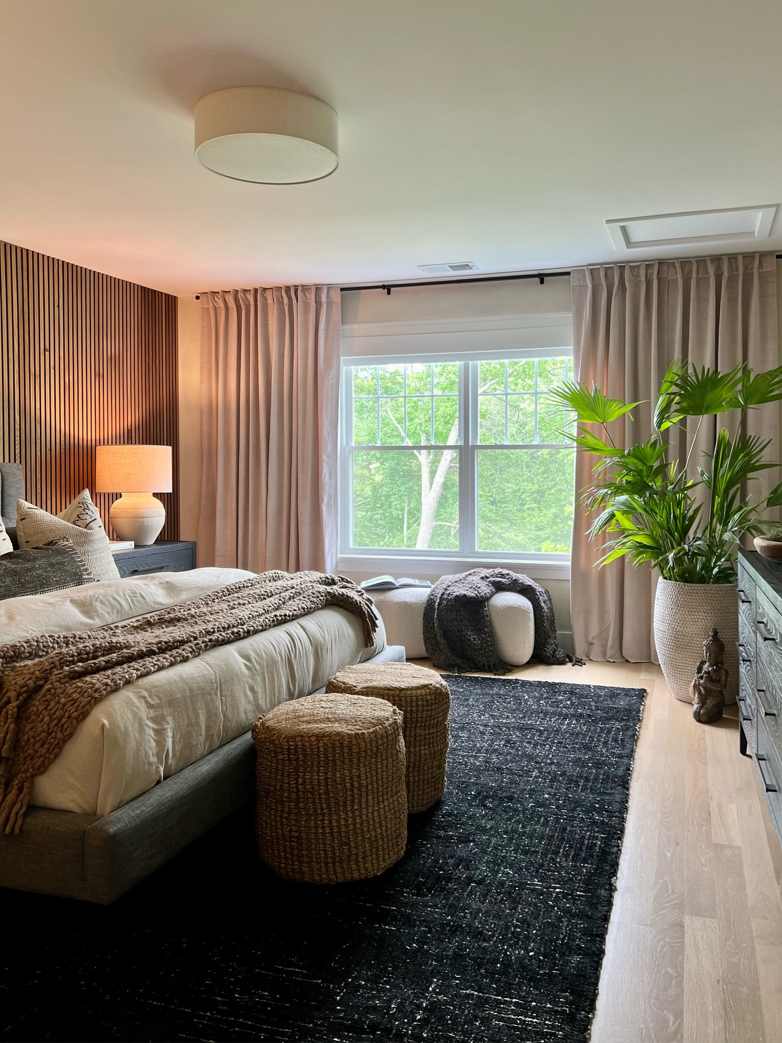 This Wabi-Sabi style inspired master bedroom design is one of my favorites. It incorporates a blend of imperfect natural elements to create the perfect serene space. Here I added a beautiful black wool rug, chunky knit black and brown throws, textured poufs, a June bench, beautiful neutral and textured pillows with a linen duvet cover to create a calming environment. To add to the serene factor, I added a kneeling Buddha statue, and a beautiful ceramic vase. Lastly I also added a flush mount light and tall curtains to add height to the room. Wouldn’t you want a bedroom like this?

#LTKFind #LTKstyletip #LTKhome