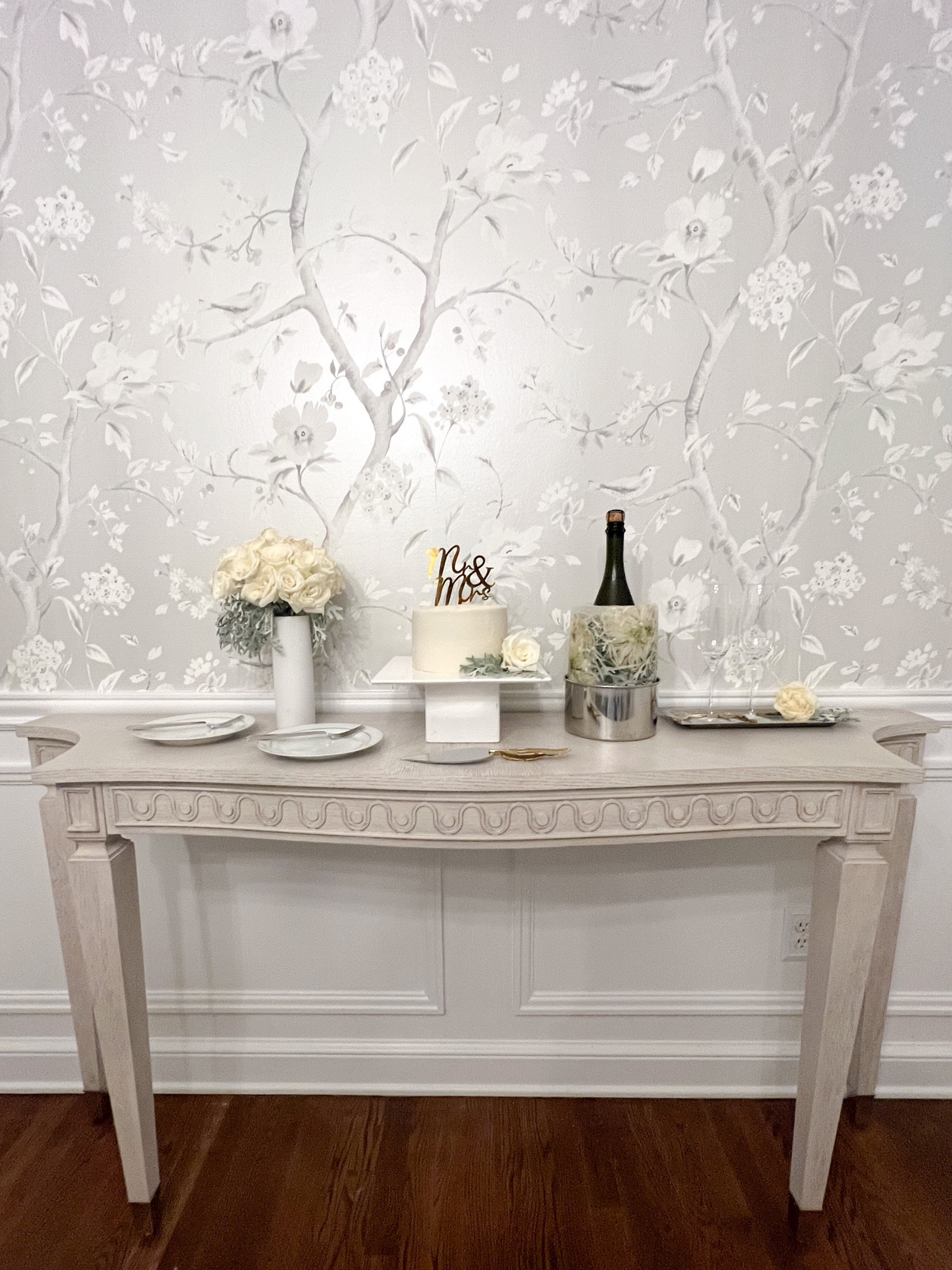 A little diy wedding cake dessert & champagne set up at home on our dining room console table. DIY white rose floral bouquet held in a white vase, cake stand with 6” buttercream cake, and a floral filled ice mold champagne bucket with a gold flower cake knife server & coordinating gold feather tray for the glassware. Traditional, grandmillenial, French, home decor, entertaining at home  

#LTKunder100 #LTKwedding #LTKhome