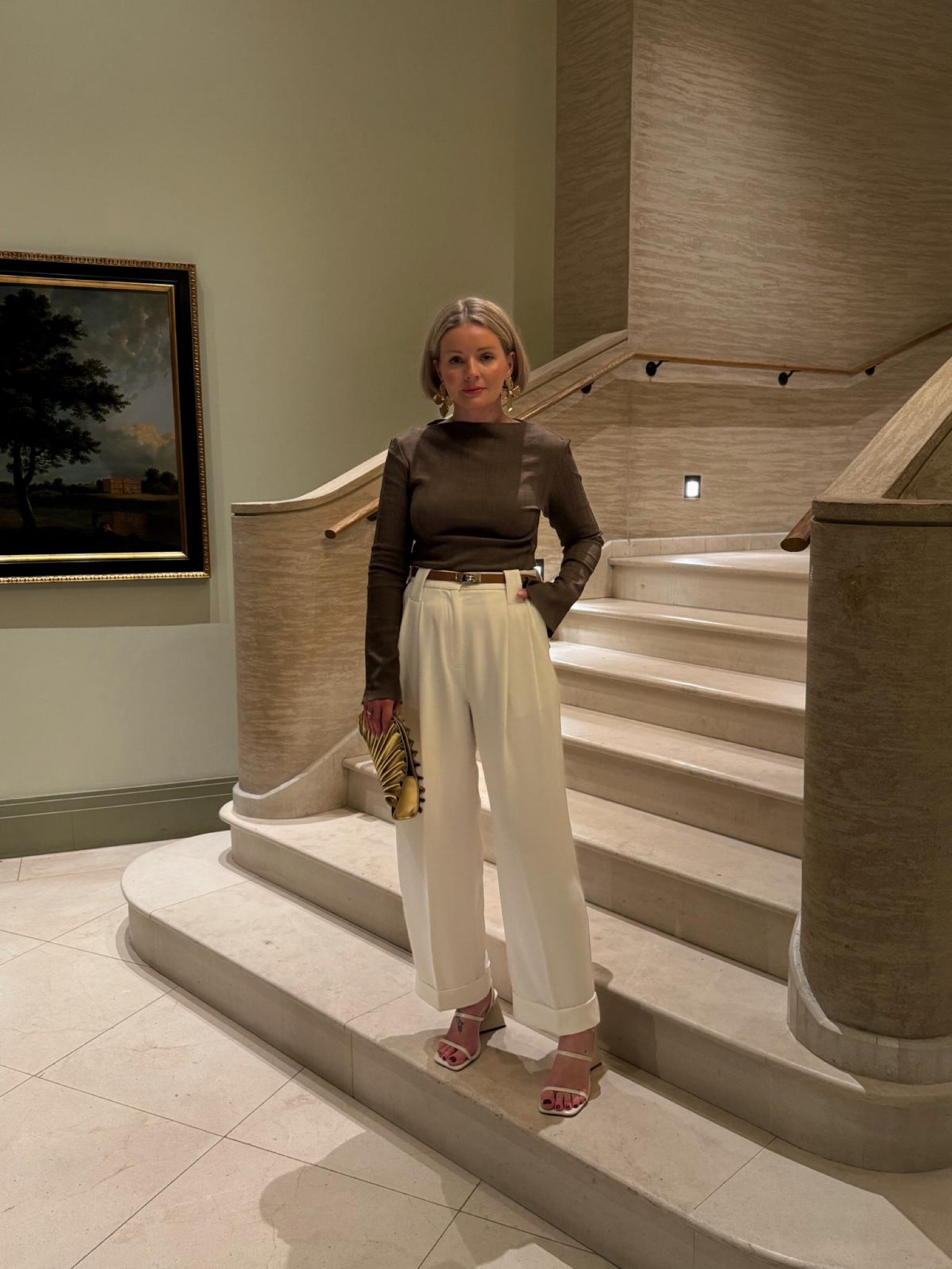 Date night spring outfit idea - white tailored trousers, khaki & other stories plisse long sleeve top, cult Gaia gold clutch bag, white heeled sandals, oversized flower earrings & tan Kelly belt  

#LTKSeasonal #LTKeurope #LTKstyletip