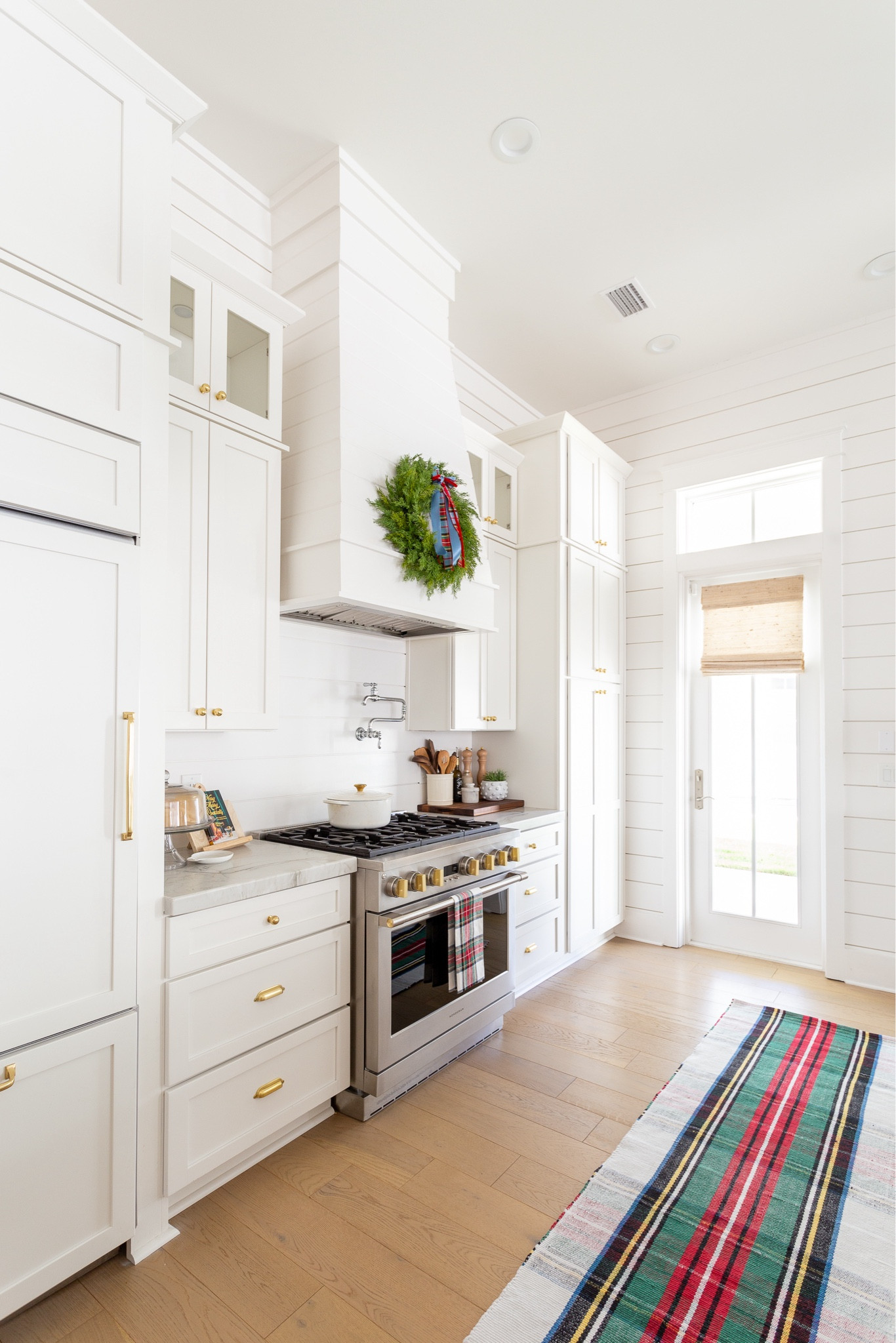 Our coastal kitchen with white cabinets and white oak floors, decorated for Christmas with a tartan plaid rug, real-touch wreath, Christmas bows, flameless candles pillars, scalloped woven chandeliers, and Christmas hand soap. #ltkhome #ltkholiday #ltkseasonal #ltkfindsunder50 #ltkfindsunder100 #ltkstyletip #ltksalealert 

#LTKHome #LTKSaleAlert #LTKHoliday