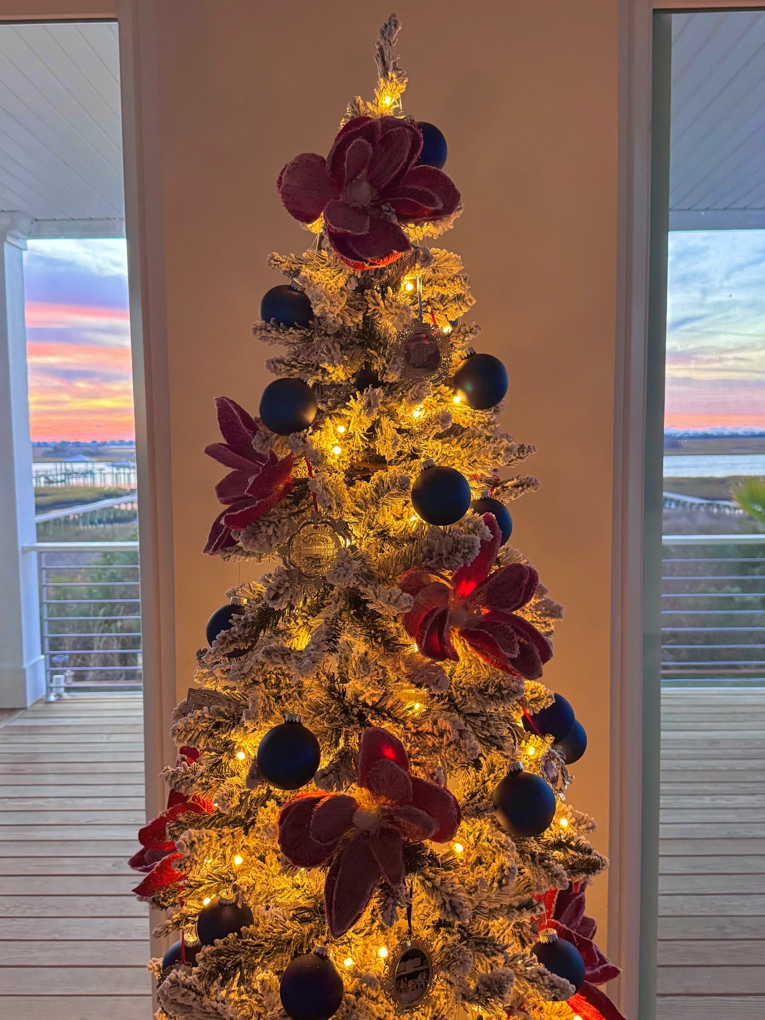 A Coastal Tree ties together interior colors of navy and the delicate blue undertone of this flocked tree which is under $75 and the contrasting Jeweled Red Magnolias with the colorful sunrise

#LTKSeasonal #LTKHoliday #LTKHome