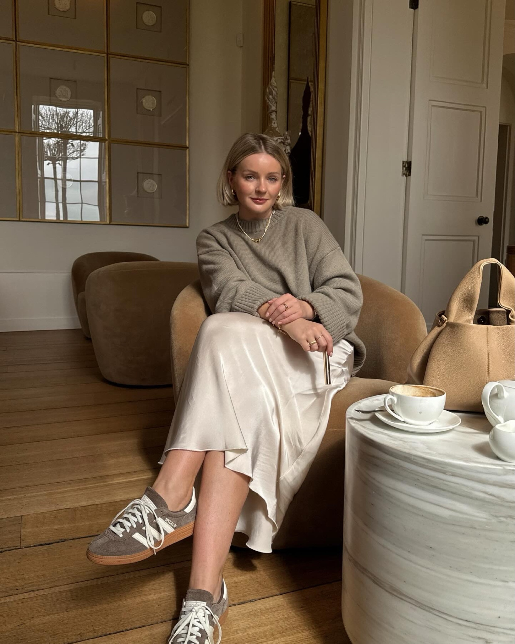 Cream satin skirt paired with a cashmere knit and adidas spezial trainers 