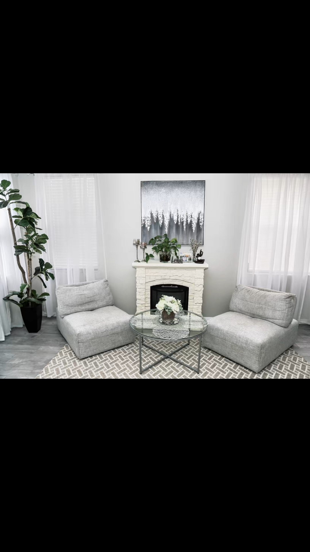 Living Room Inspiration 🤍
Looking for a cozy yet sophisticated space to unwind in style? This living room decor is giving all the serene vibes! From the clean, modern lines to the subtle pops of texture, every detail adds a layer of calm elegance.

Key Design Elements:
✨ Neutral Palette: The soft grays and whites keep the space bright and airy, perfect for creating a relaxing atmosphere.
✨ Layered Textures: Check out the interplay of the plush seating, woven rug, and the stone-like fireplace surround—textures make neutrals anything but boring.
✨ Natural Accents: The fiddle-leaf fig in the corner and fresh greenery on the mantel bring a touch of nature indoors, balancing the space beautifully.
✨ Statement Art: The abstract piece above the fireplace ties everything together with its monochromatic charm.

Styling Tips:
	•	Swap out the coffee table decor with the seasons for a quick refresh.
	•	Use sheer curtains like these to diffuse natural light while maintaining privacy.
	•	Mix metals and natural tones to add dimension without overwhelming the space.

Shop this look now and turn your home into the sanctuary you’ve been dreaming of. 🪴💫
