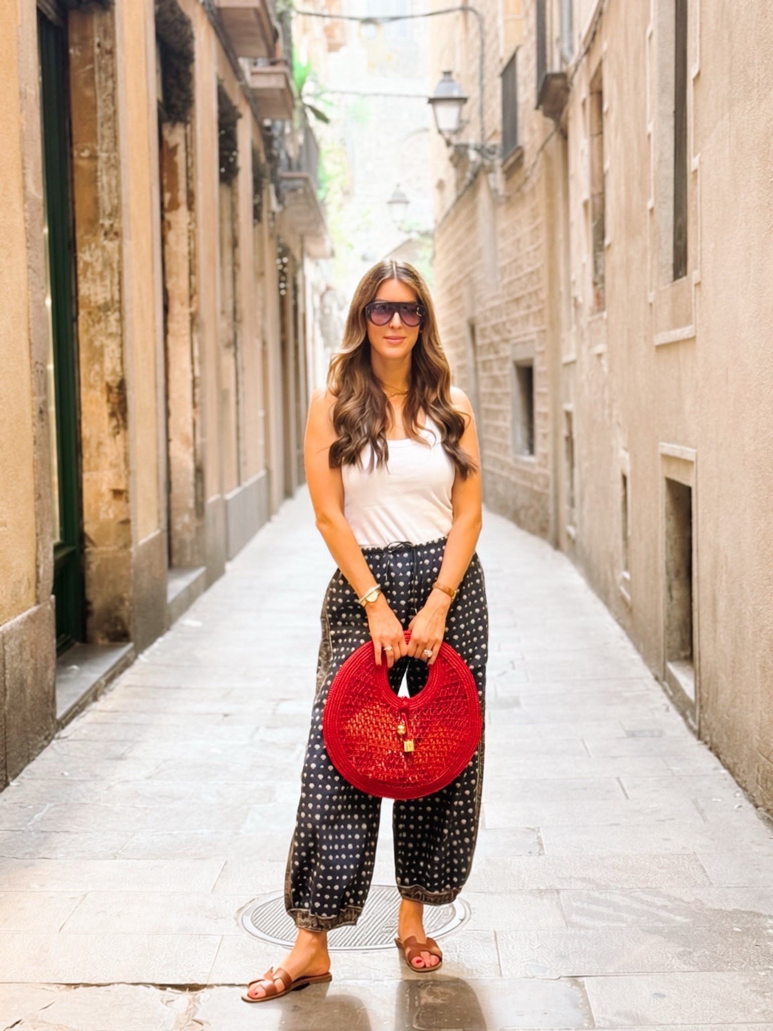 A simple outfit that felt so right for wandering beautiful Spain. 🤍 These DÔEN navy pants are one of my favorite purchases (I'll link this color and similar options!), paired with a classic tank and my go-to sandals. Finished with a pop of red thanks to this Jacquemus bag—which lays completely flat, making it the perfect vacation handbag to pack.

#LTKootd #LTKOver40 #LTKTravel