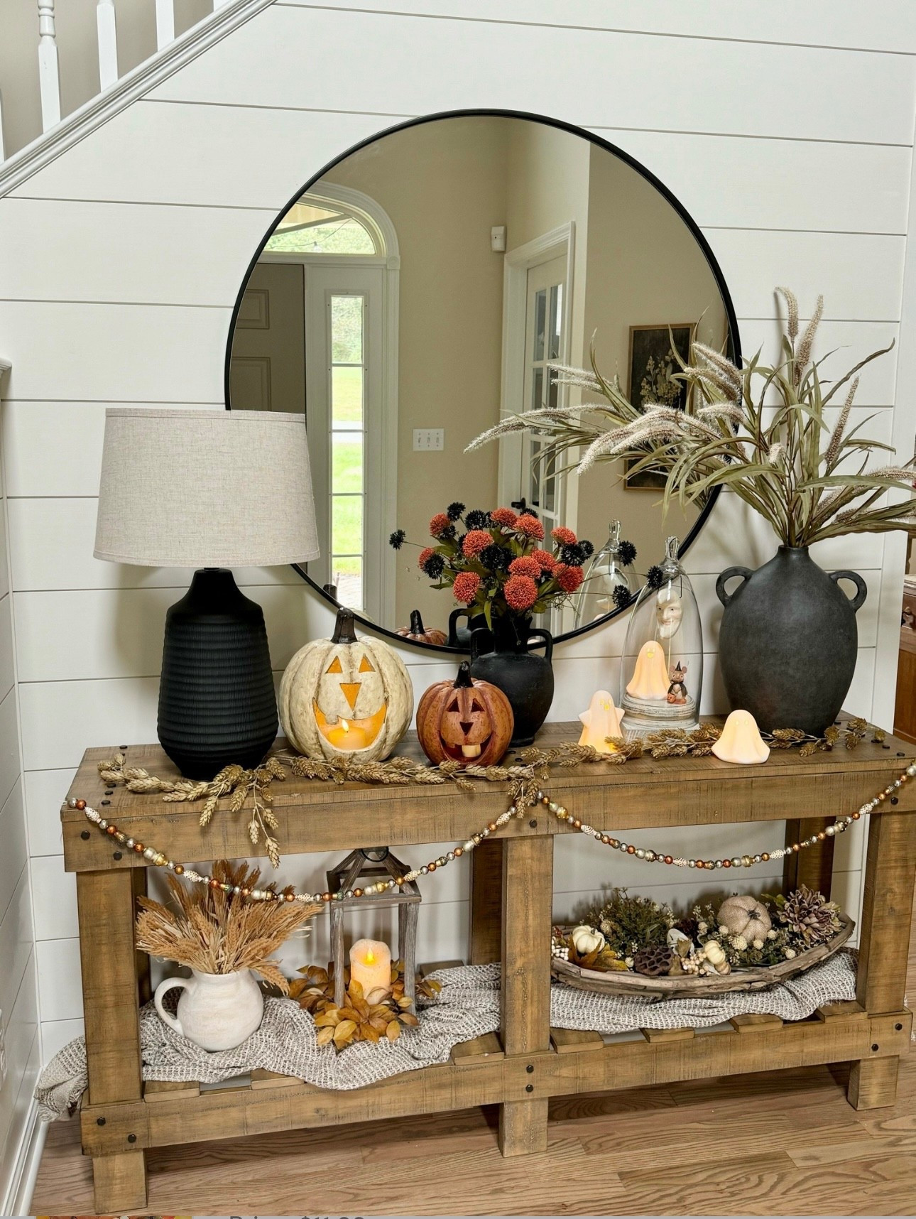 Fall and Halloween table decor. Orange and white wide mouthed jack-o-lanterns. Trio of ceramic led light up ghosts. Black floral stems. Rust and wheat floral stems. 42” Round Mirror. Rustic console table. Black lamp, black vase, similar dough bowl and gourds  

#LTKHome #LTKSeasonal