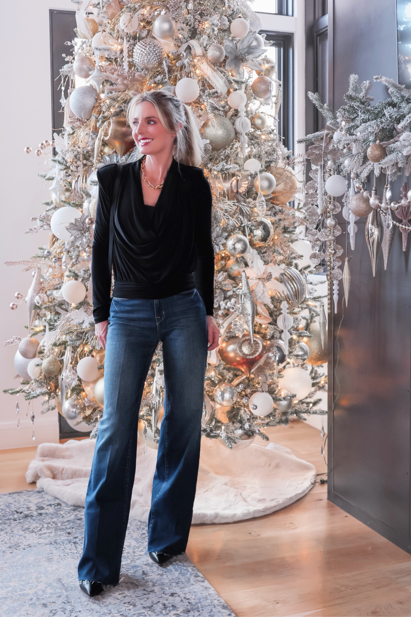 This elegant black top from @saks is one of my favorite tops of the season! It has structured shoulders, a cowl neck, and it drapes so beautifully. The gathered waistband helps create a waist and covers the top of the jeans, but it is on the shorter side, which might be a consideration for those of you who are tall or have a longer torso. I’m wearing a black bralette underneath to provide more coverage, but you can try a normal black bra too. I think wearing the bralette is just easier, so you don’t have to worry about a wardrobe malfunction. When I wear it with a regular bra, I just use double-sided tape to keep anything from showing. Fit runs true to size. 
#saks #sakspartner

I styled the top with a pair of jeans that deserve their own spotlight. They are *maybe* the MOST comfortable pairs of jeans I’ve ever put on my body. If you’re a longtime subscriber, you understand the gravity of that comment, because I own a LOT of jeans. They’re incredibly soft and lightweight, they drape so well, aren’t tight anywhere, and feel great on the waist and tummy. I love the flattering wide legs and the loose, trouser-like fit. They run a little big, grab them in a size down from your normal size.

To complete the look, I added a chic Loeffler Randall crossbody bag, an Alexis Bittar gold necklace, and a pair of black booties by Schutz (true to size).

And right now, if you spend $150 at Saks, you’ll get $75 gift card with code BFGIFTSF. ✨

~Erin xo

#LTKSaleAlert #LTKHoliday #LTKStyleTip