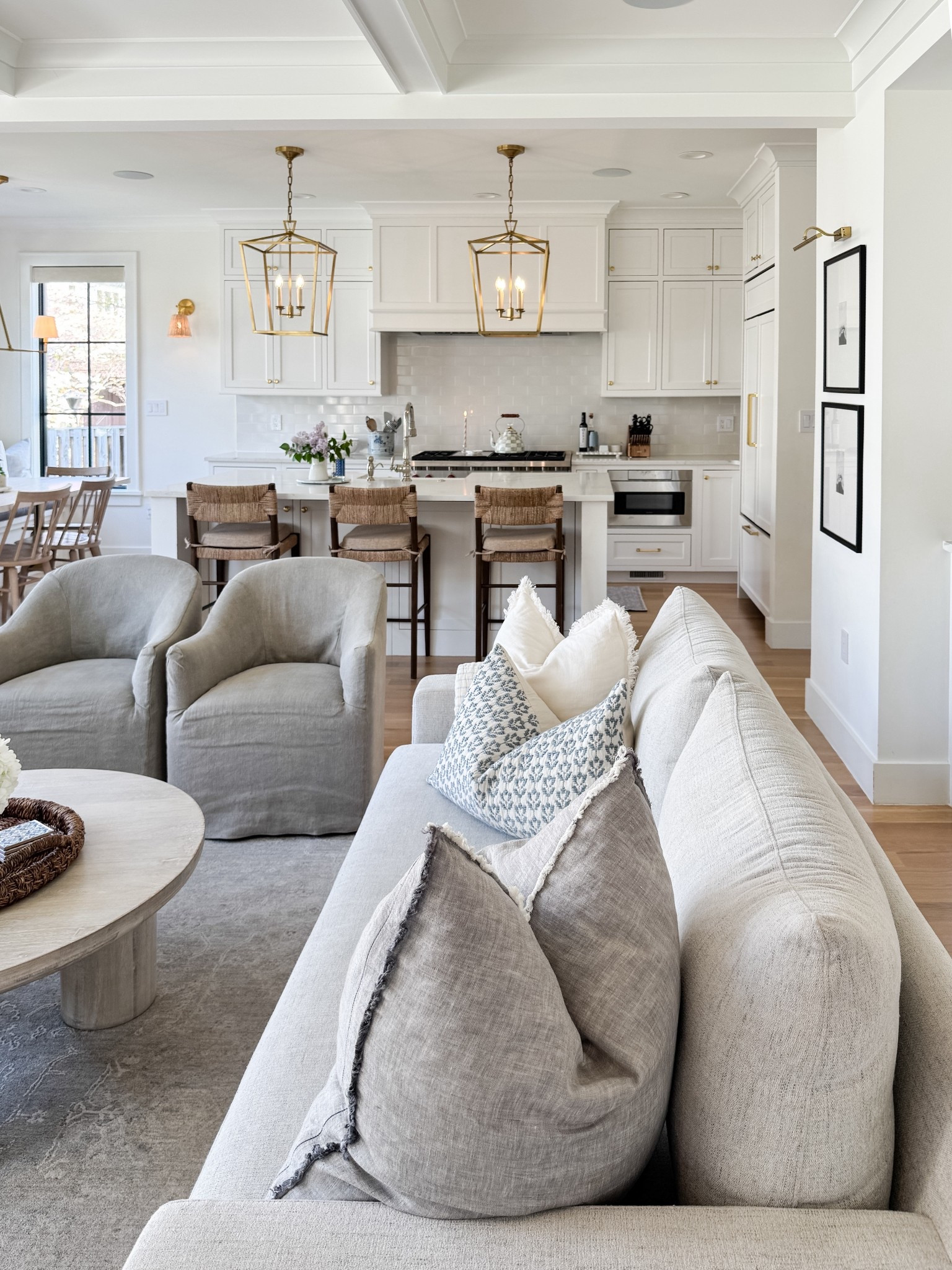 Open concept, living room and kitchen. Light and airy, white cabinetry, brass lanterns, muted sofa and small accent chairs.

#LTKmomlife #LTKHome #LTKSaleAlert
