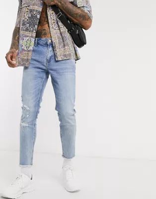 ASOS DESIGN cropped skinny jeans in light wash with raw hem and busted knee | ASOS (Global)