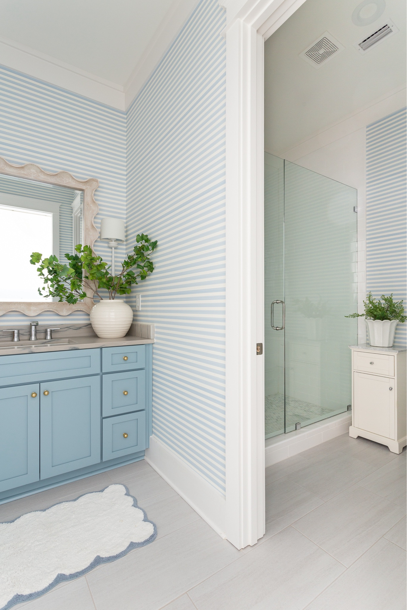 Our light blue striped bathroom decorated for fall! We love the gold knobs on our blue cabinets, blue striped wallpaper, scalloped bath mat, faux ginkgo stems, ribbed white vase, and scalloped hand towel! Also linking our white sconces and scalloped wood mirror. See more here: https://lifeonvirginiastreet.com/coastal-bathroom-wallpaper/.
.
#ltkhome #ltkseasonal #ltksalealert #ltkstyletip #ltkfindsunder50 #ltkfindsunder100 coastal decor, coastal fall decorating ideas #LTKsalealert #LTKhome

#LTKSaleAlert #LTKSeasonal #LTKHome