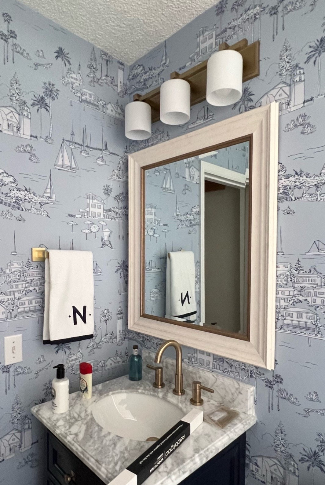 Costal bathroom wallpaper, wallpaper for bathrooms, beach inspired wallpaper and decor for bathroom, Florida styled bathroom with wallpaper. This Serena and Lily wallpaper is the perfect way to create a blue/airy and costal bathroom for this Florida bathroom renovation! Toile wallpaper, teak stool, marble trash can, rattan mirror, bathroom wallpaper sconce 
#diywallpaper #bathroomwallpaper #nauticaldecor #serenaandlily #costalbathroom #beachhomedecor #costalcottage Home decor and renovation, Florida styled, blue bathroom 

#LTKSeasonal #LTKHome #LTKSaleAlert