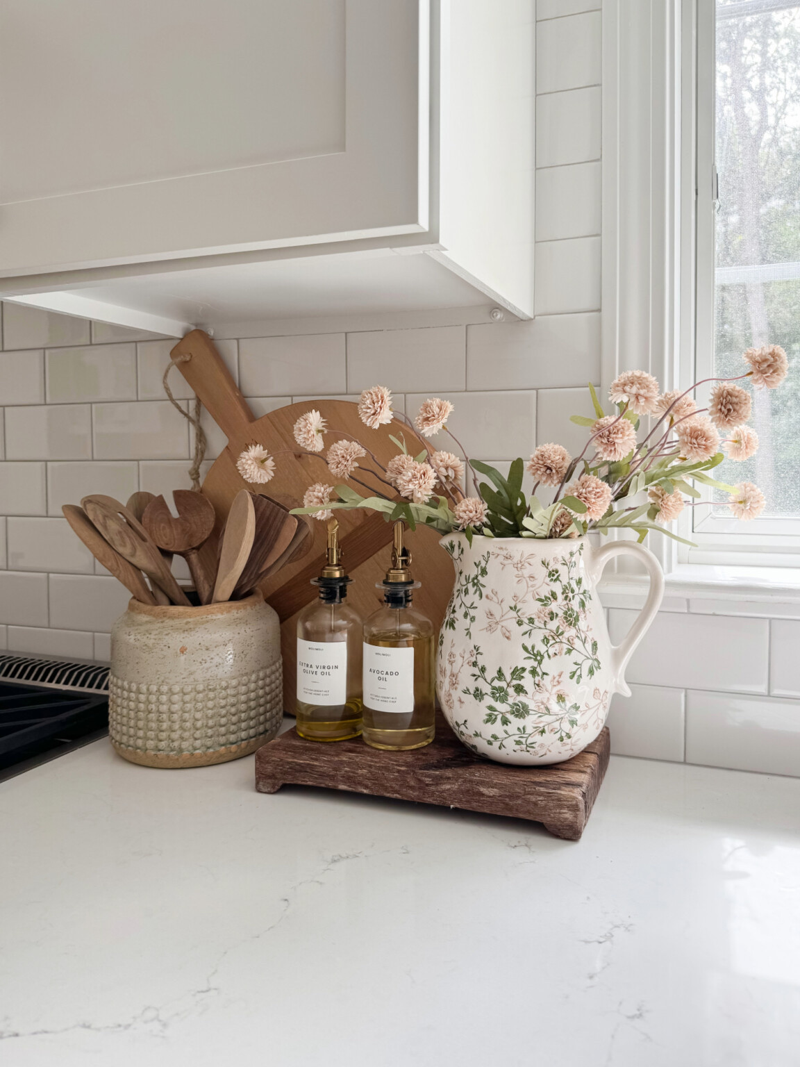 Kitchen countertop styling with oil and vinegar dispensers, floral pitcher vase, silk mums, and wood cutting boards for warm neutral kitchen decor.

neutral kitchen styling, oil and vinegar dispensers, floral pitcher vase, silk mums decor, kitchen counter styling, wood cutting boards decor, neutral kitchen accessories, coastal kitchen decor, sherricalnanhome

#LTKHome