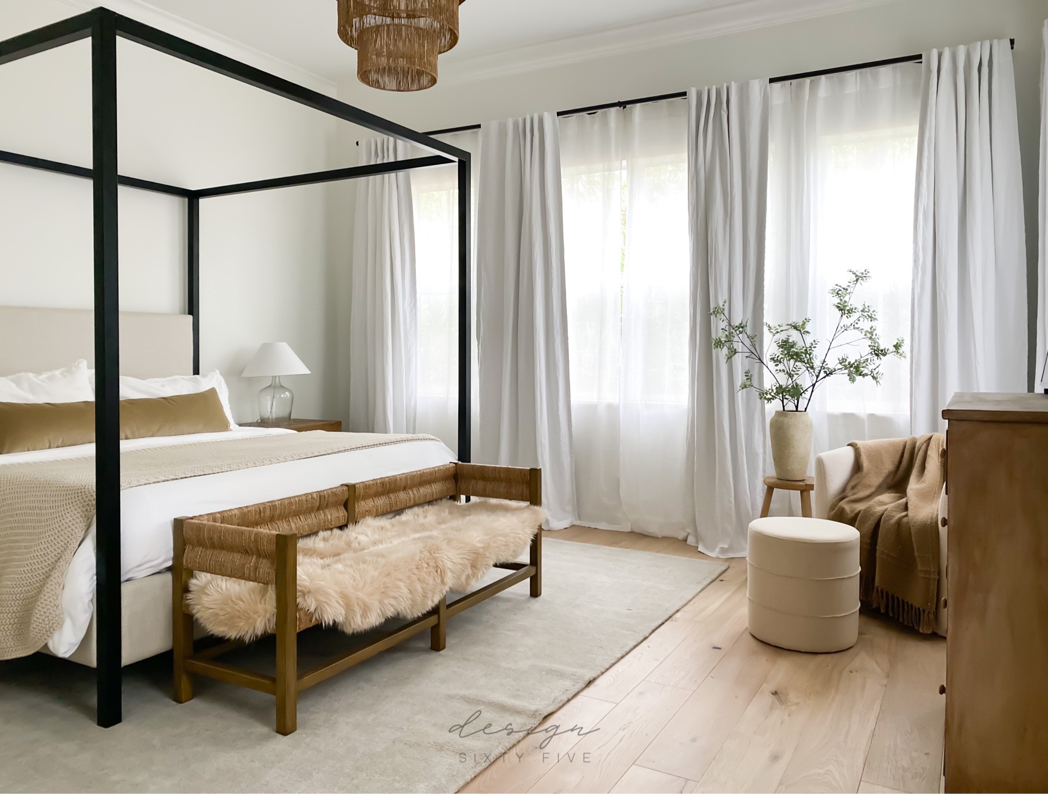 Neutral bedroom decor, black canopy bed, end of bed bench, nightstands, long lumbar pillow, table lamps, candle sconces, neutral rug, linen curtains, woven chandelier 

#LTKhome