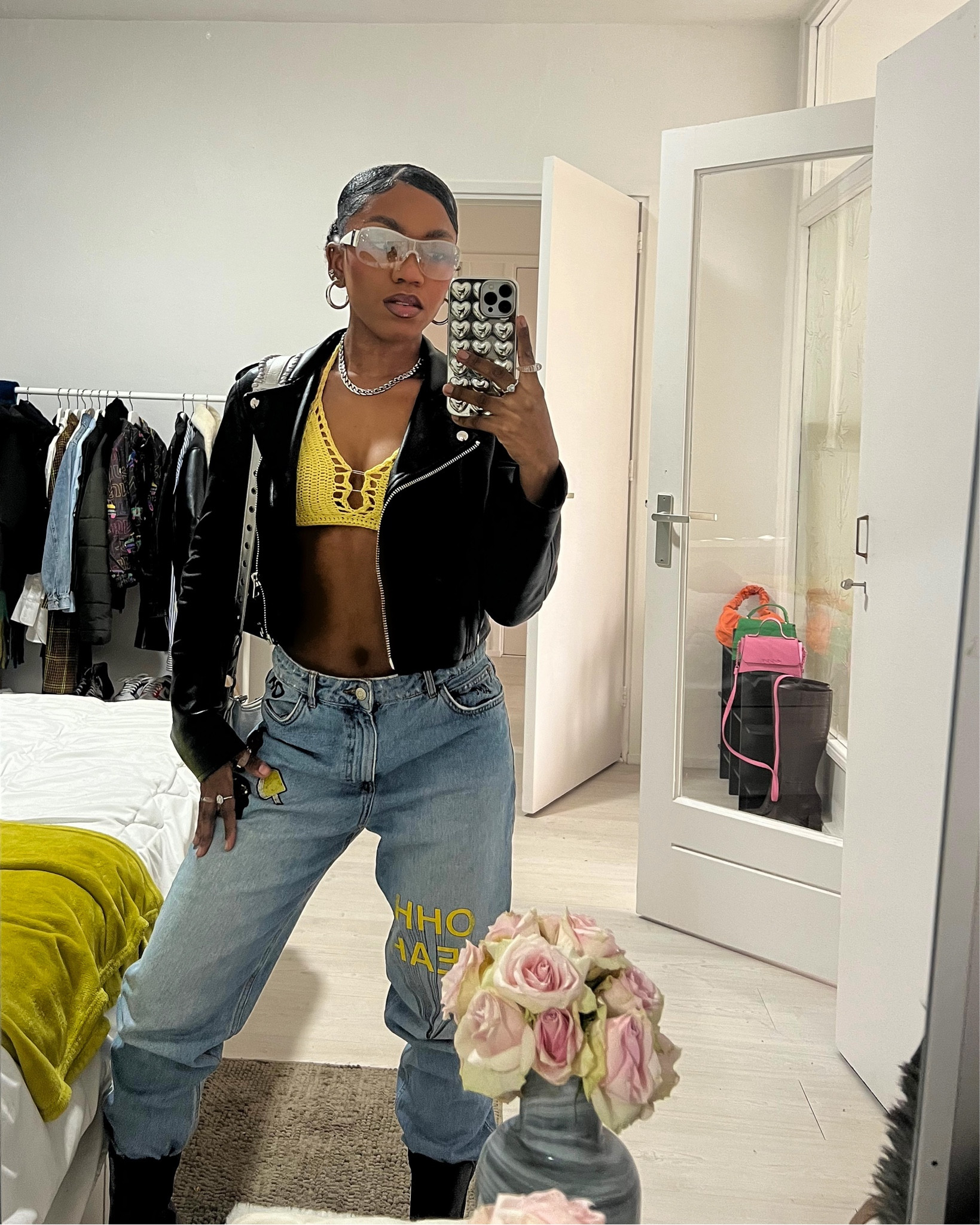 Streetwear fashion. Black and yellow outfit. Bershka black leather biker jacket. Thrifted ZARA graffiti patched light blue jeans. Yellow crochet top. H&M Y2K silver sunglasses. Silver accessories. Silver bag. Silver SHEIN heart iPhone case. NYC fashion style. Sophisticated fashion. Trendy fashion. Trendy style. Crop top, denim and jacket outfit. 

#LTKSeasonal #LTKstyletip #LTKfit