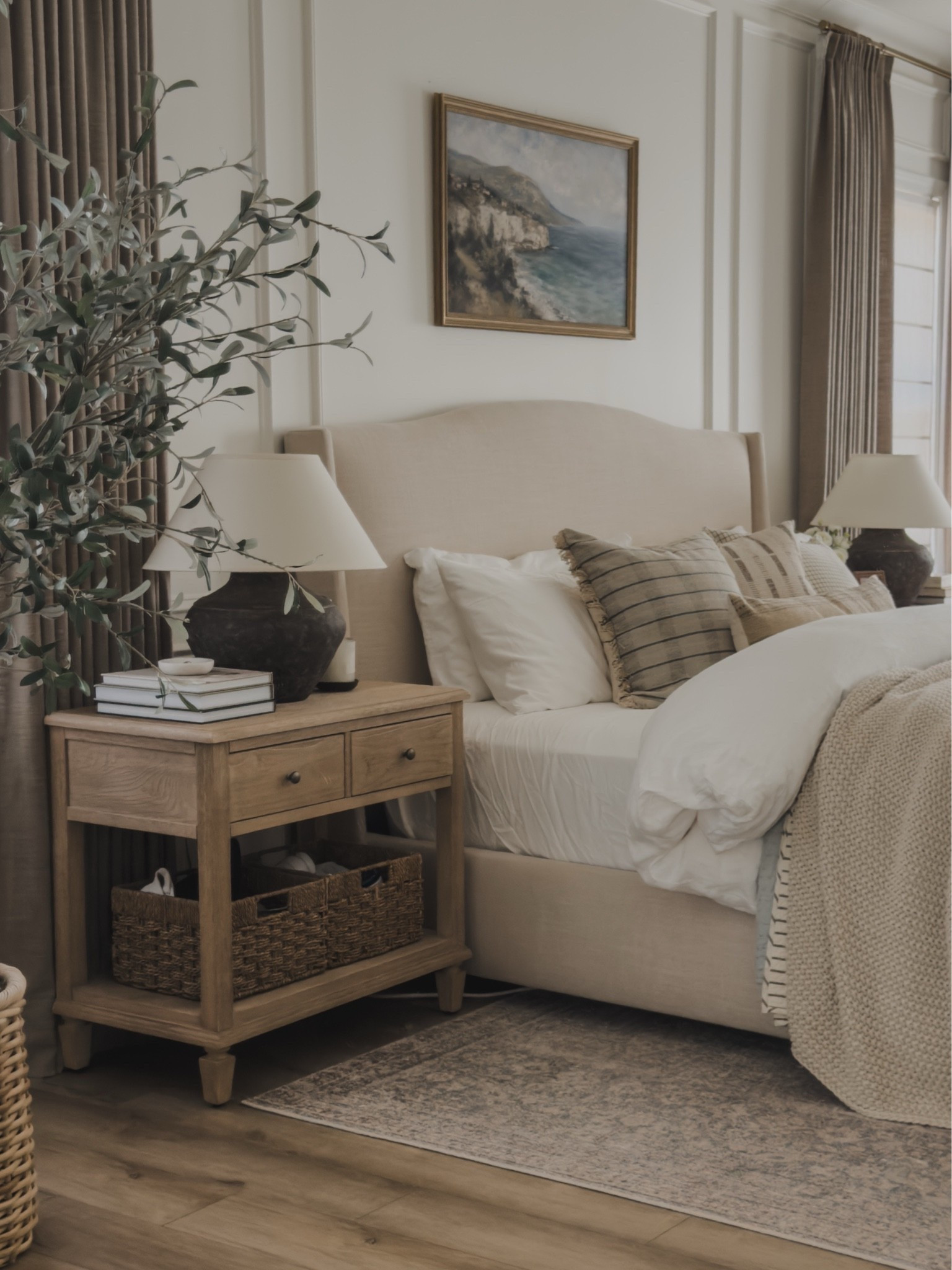 Sharing a closer view of my primary bedroom! I have these nightstands for several years and the quality withstands the test of time. I opted for storage baskets that add both function and aesthetic for an overall timeless and cozy look.

Home finds, neutral home inspo, neutral wood tones, furniture favorites, primary bedroom details, early fall transition, collected style, cozy bedding, upholstered bed frame, moody table lamp, vintage style area rug, faux olive tree, pinch pleat curtain, roman linen shade, Wayfair, Pottery Barn style, Galey Alix, Two Pages, Loloi, Amber Lewis, Etsy, shop the look!

#LTKSeasonal #LTKHome