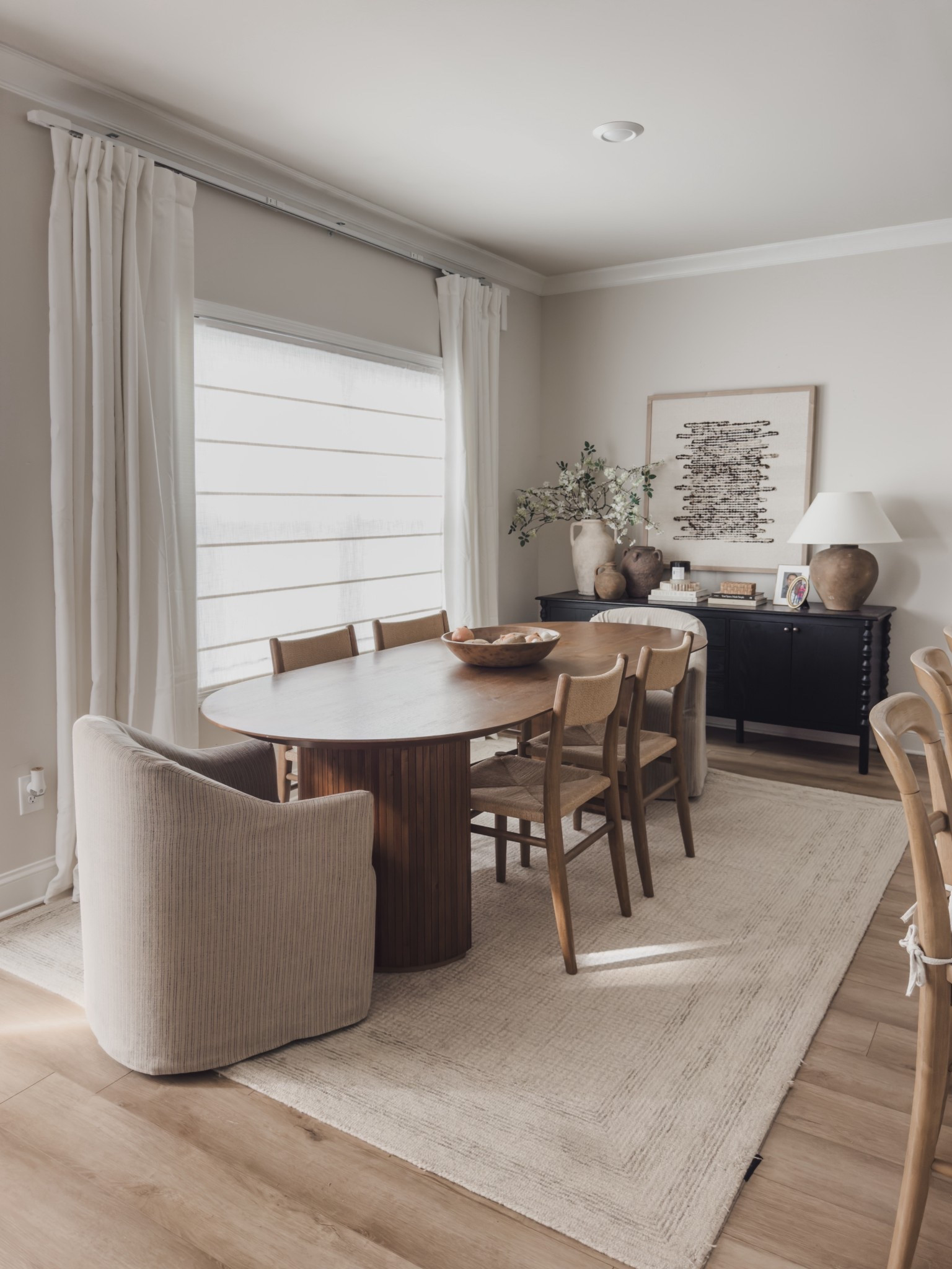 Sharing all of the dining room details.

I’m always focused on quality pieces that can actually hold up to real life — kids, everyday use, and a few messy goldendoodles running through the house. Pretty is great, but it also has to function well for our day to day.

Our oval dining table has been holding strong for almost three years now and still looks just as beautiful as the day we got it. I love the shape for this space — it softens everything and makes it feel really inviting when everyone gathers around.

The oak dining chairs have the prettiest paper rush detail that adds just the right amount of texture while still keeping the room neutral and timeless. On the ends, I added subtle striped slipcovered chairs that roll, which makes them super practical but still feel soft and tailored.

Underneath everything is this wool rug with the most subtle print. It’s actually the same rug I used in our living room before moving it in here, and it has held up incredibly well over time.

And the buffet might be one of my favorite pieces in the room. It could easily work in an entryway too. Ours has unfortunately been discontinued, but Lulu and Georgia sells an almost identical piece that actually has shelves inside — which I might like even more.

World market, Lulu and Georgia, rugs direct, kivhtopia, fourhannds, 