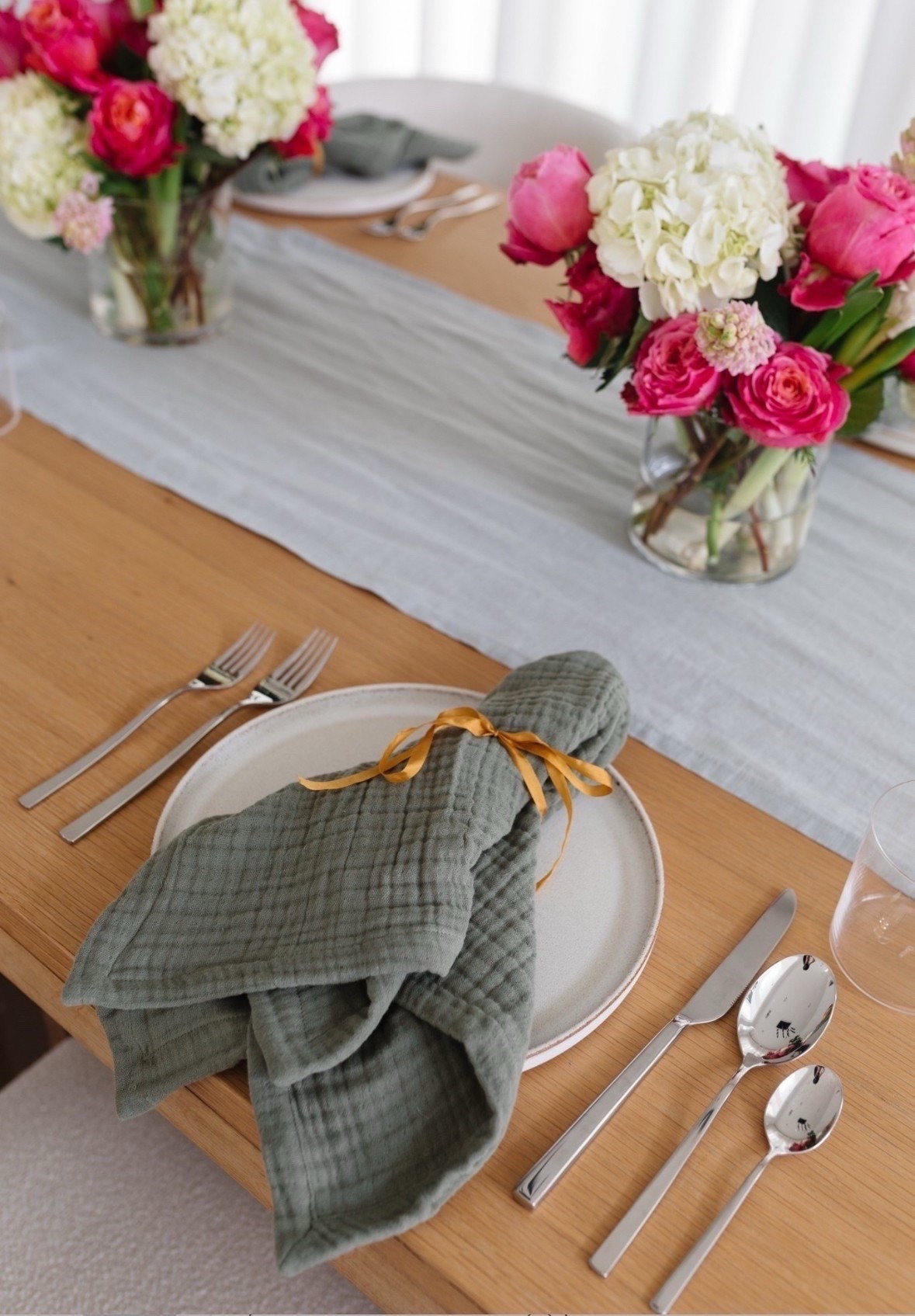 Spring tablescape with silver flatware, glass cups, mist linen runner, and olive napkins that are so pretty! Perfect way to add a pop of color into your spring hosting. 

#LTKHome