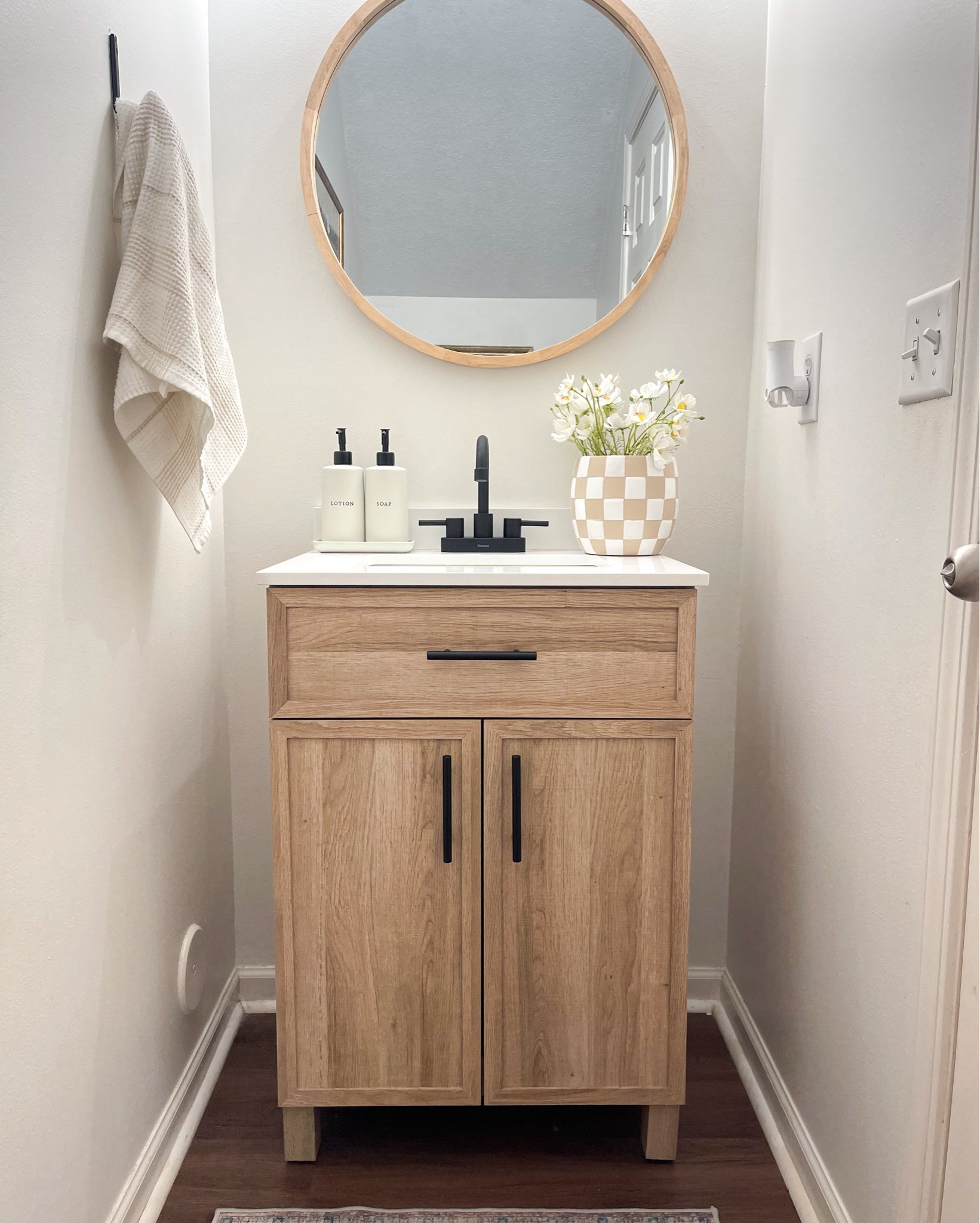 Half bathroom ideas. Checkered planter. Honey oak bathroom vanity sink. Round wall mirror. Gold bathroom sconce light. Black faucet. Soap dispenser. Persian area rug. Wall art. 

#LTKHome #LTKGiftGuide #LTKStyleTip