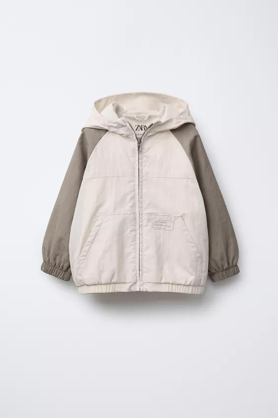 Lightweight, long sleeve raincoat with a hood and contrast colour elasticated cuffs. Zip-up front... | Zara UK
