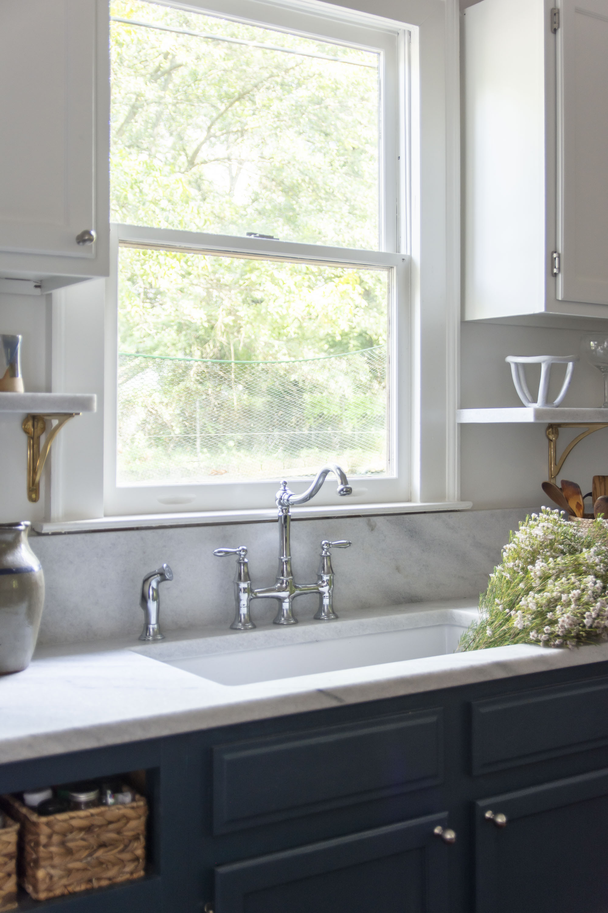 Blue kitchen cabinets with white marble countertop, brass shelf brackets, polished silver chrome bridge faucet with pull out sprayer, and white porcelain farmhouse sink kitchen design and renovation ideas  

 

#LTKHome #LTKStyleTip