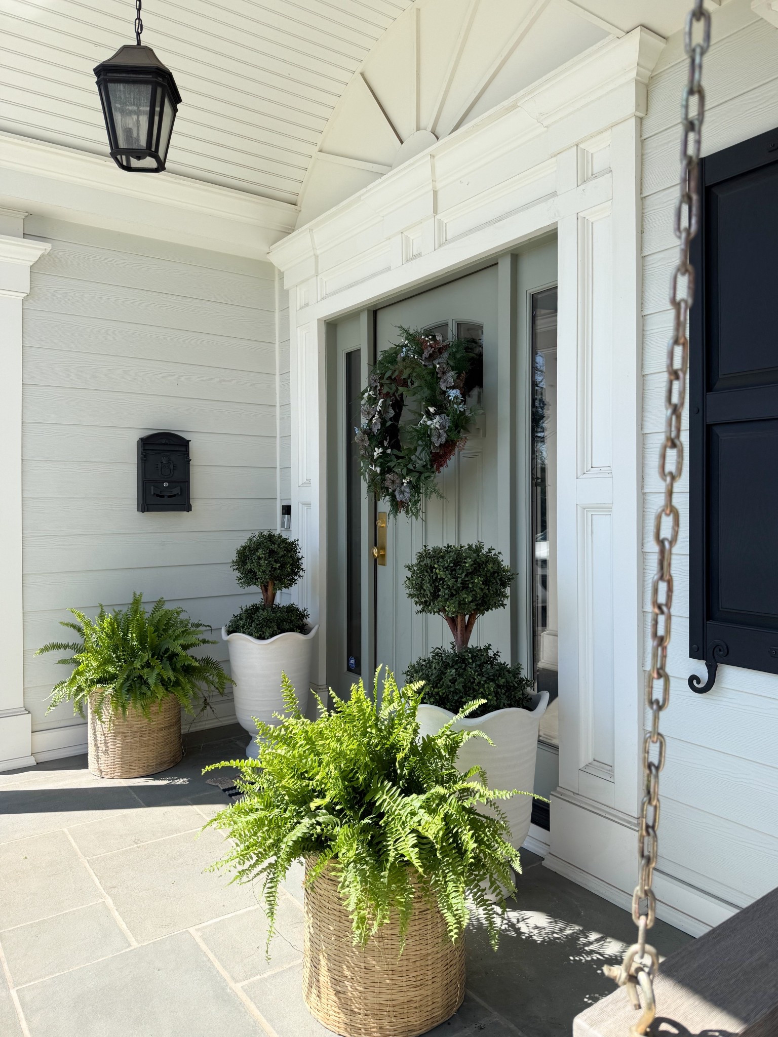 This front porch setup shows how mixing structured and organic elements can create such a balanced, elevated look. The classic urn planters with topiaries bring in that polished feel, while the woven baskets and full ferns soften everything with texture and movement. Paired with the greenery wreath, it all comes together in a way that feels layered, intentional, and easy to recreate.

front porch decor ideas, outdoor planter styling, woven planter baskets, classic urn planters, topiary front porch, greenery wreath decor, layered outdoor decor, neutral exterior design, entryway curb appeal, outdoor greenery styling, welcoming front porch girlonthehudson

#LTKSeasonal #LTKHome