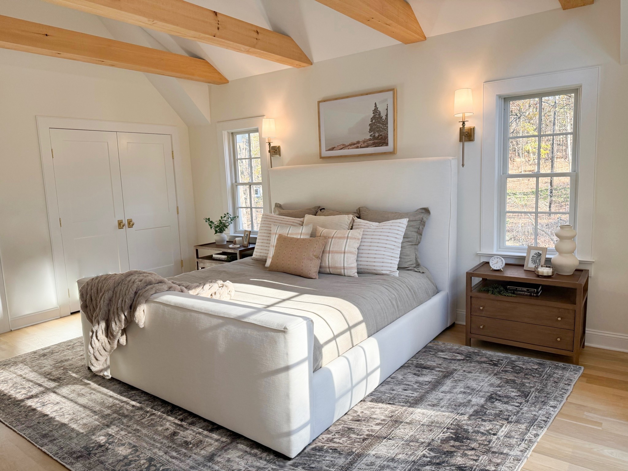 An angled view of the Mount Kisco primary bedroom reveals its thoughtful design and layered textures. The upholstered bed is framed by cozy bedding and a soft area rug that adds warmth underfoot. Every detail—from the layered linens to the subtle color palette—creates a restful and beautifully curated retreat.