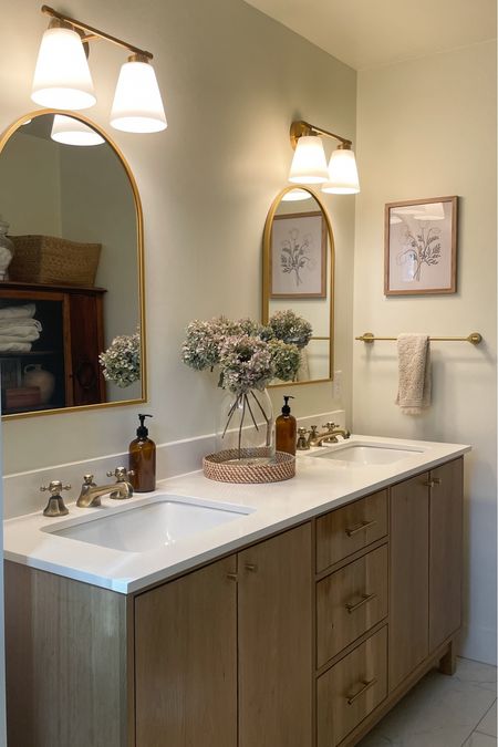 Our master bathroom is calm and serene.  It looks expensive but it’s actually affordable.  

Master bathroom.  White oak double vanity.  Kohler sinks.  Arched bathroom mirror.  Brass wall sconces.  Double mounted wall lights.  Antique brass widespread bathroom faucet.  Kingston Brass.  Lowe’s 12X24 porcelain floor tile. 

#LTKHome #LTKFamily