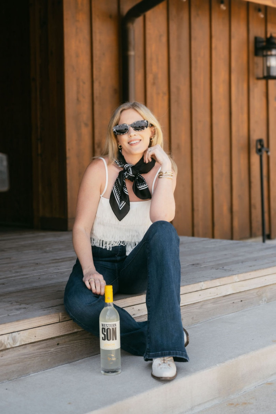 Western look 
Western style 
Fringed top 
Fringe tank 
Black bandana
Square sunglasses 
White cowboy boots 
Free people wide leg jeans  

#LTKSeasonal #LTKFindsUnder100 #LTKFindsUnder50