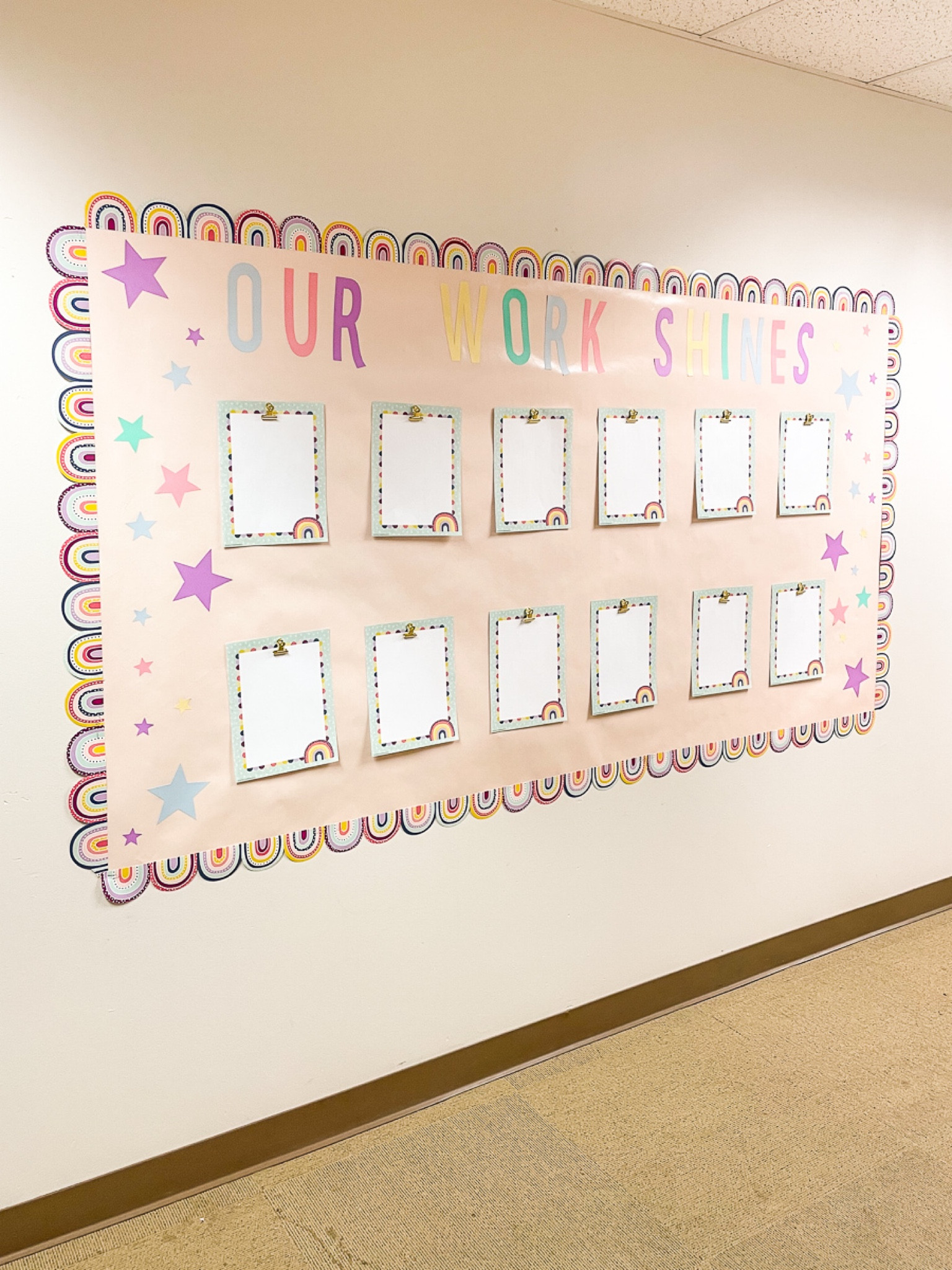 Classroom Decor - Student Art Display! 

At the entrance is also the student art display where students can show off their best work. For this section, I used this pretty blush bulletin board and got coordinating rainbow border trim to frame it. The gold clips are actually wall pins and can clip student artwork. Then I used sticker cardstock to make the sign “Our Work Shines” and the pastel stars. 