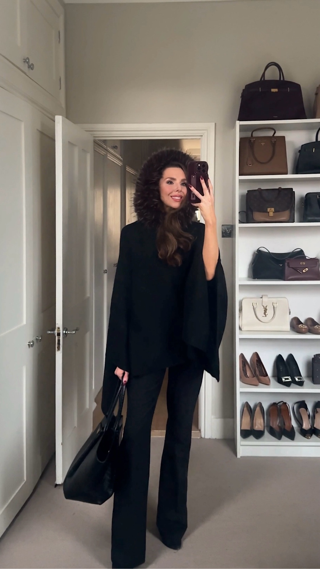 Eskimo Chic. A cosy black cape knit top with a faux fur trim hood paired with sleek black tailored trousers and black stiletto point toe sock boots. Finished with the Demellier New Yorker black tote for an elevated winter look that feels soft, cocooned, and quietly chic rather than sharp or structured. Effortless cold-weather elegance with a fashion edge.

#LTKwinter #LTKfestive #LTKuk