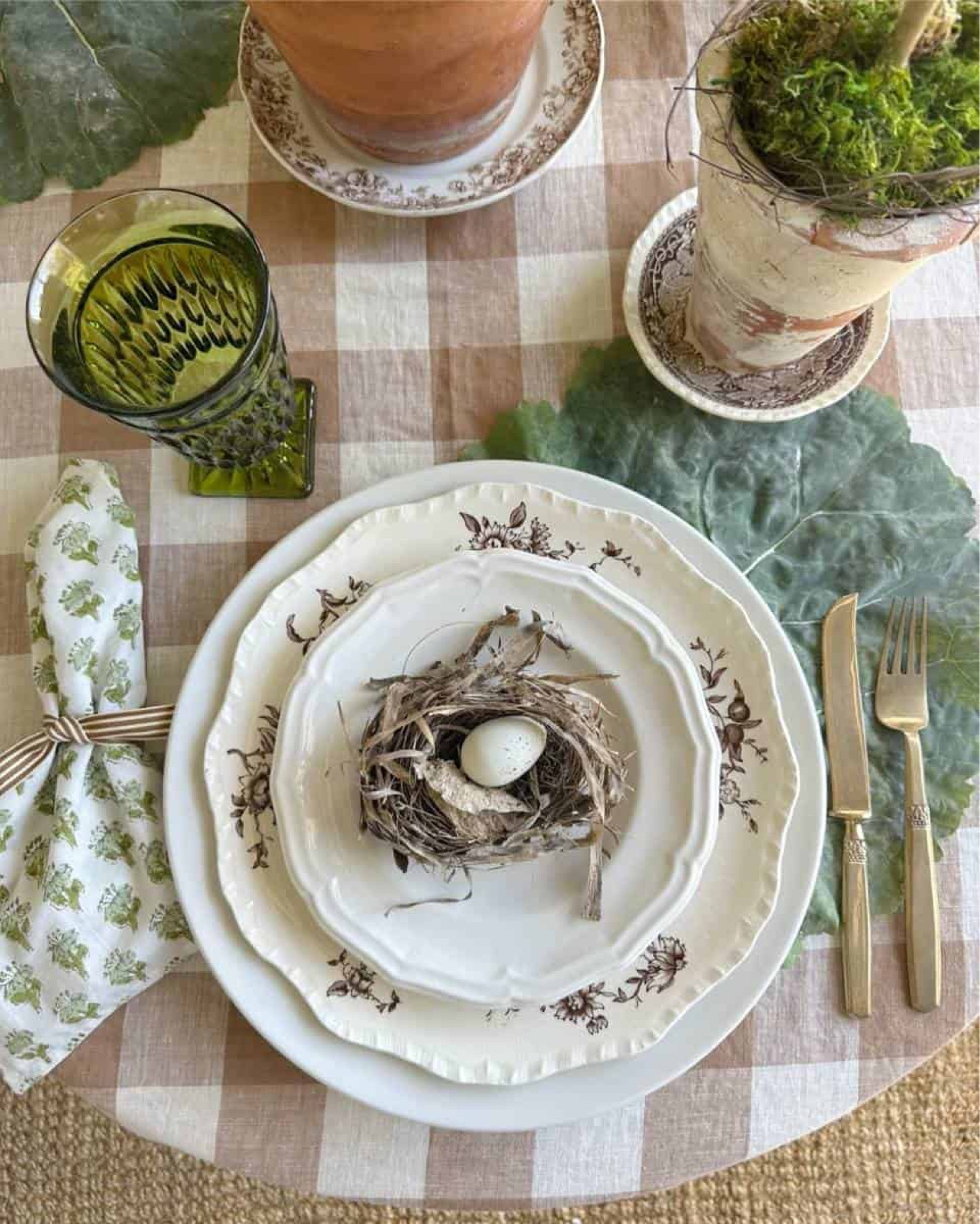 A simple Spring tablescape using a brown and white buffalo check linen tablecloth, green block print napkins, and cabbage leaf placemats.

A birds nest on top of each place setting is the perfect touch for a Spring or Easter table.

#springtable #eastertable 

#LTKSeasonal #LTKHome #LTKStyleTip