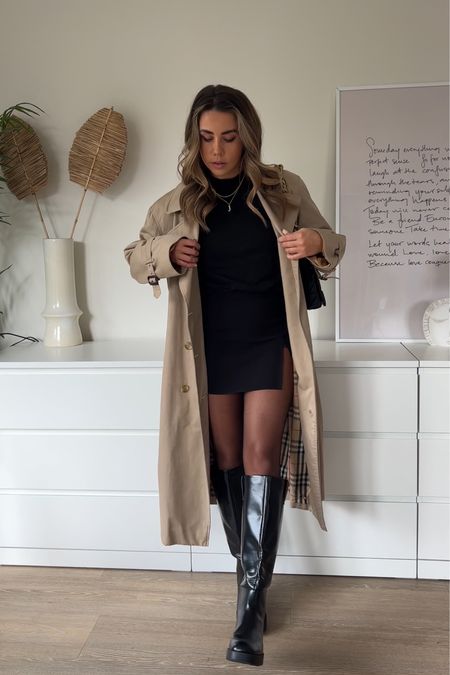 Styling a trench coat with black split skirt and knee high boots for an all black spring outfit 
