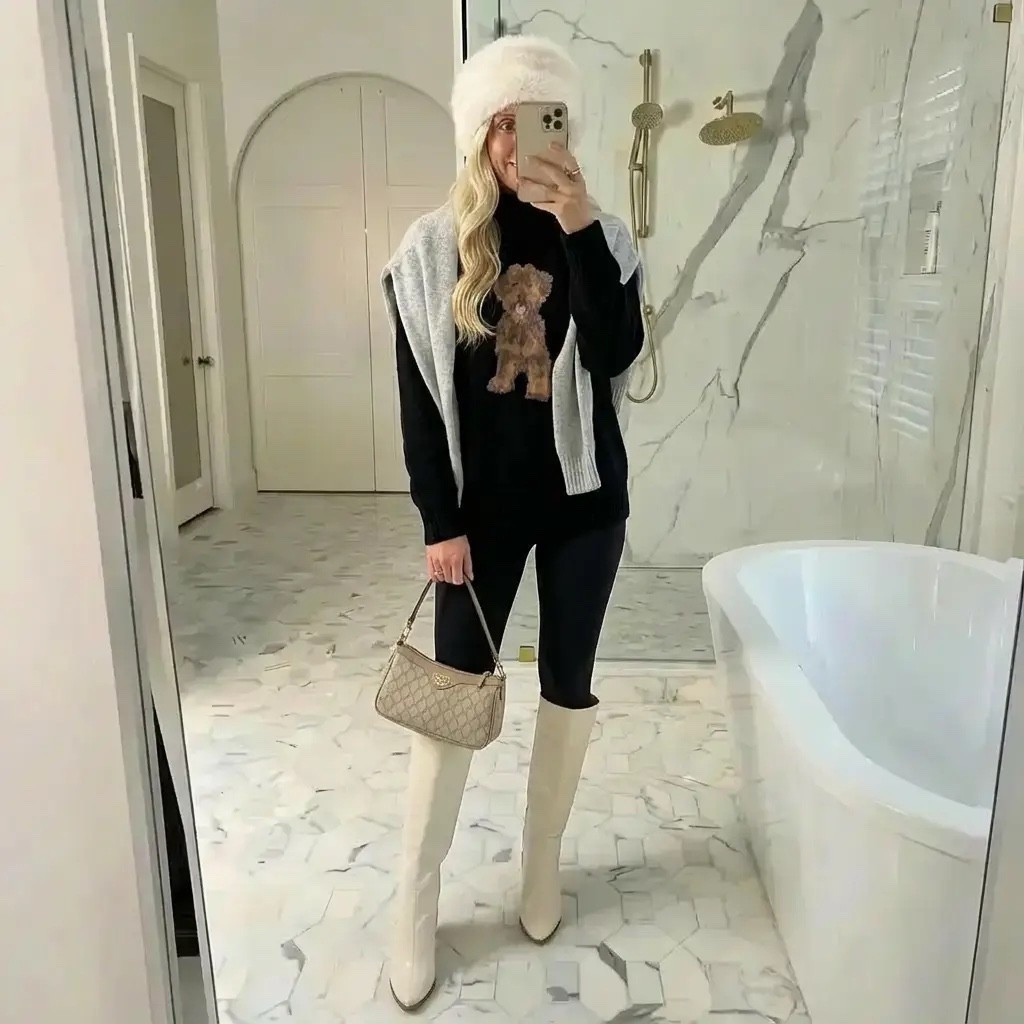 A cozy mirror selfie in a bright, marble luxury bathroom with soft natural lighting. A tall, elegant blonde woman wears an all-black winter outfit featuring a black sweater with a teddy bear motif, sleek black leggings, and cream knee-high boots. A light gray sweater is casually draped over her shoulders, and she completes the look with a fluffy white winter hat and a small beige designer shoulder bag. Her hair falls in loose, polished waves, creating an effortlessly chic, cozy-luxe aesthetic that blends casual elegance, winter style, and understated confidence.

⸻

HASHTAGS

#CozyChic
#QuietLuxury
#WinterStyle
#CasualElegance
#NeutralLuxury
#EffortlessChic
#WinterOutfit
#SoftGlam
#LuxuryAesthetic
#CoolGirlStyle
#EverydayChic
#MirrorOutfit
#OOTD
#OldMoneyVibes
#WinterLayers
#ChicComfort
#FashionInspo
#MinimalistStyle
#MainCharacterEnergy
#WinterLook



#LTKHoliday #LTKdayinmylife #LTKGiftGuide