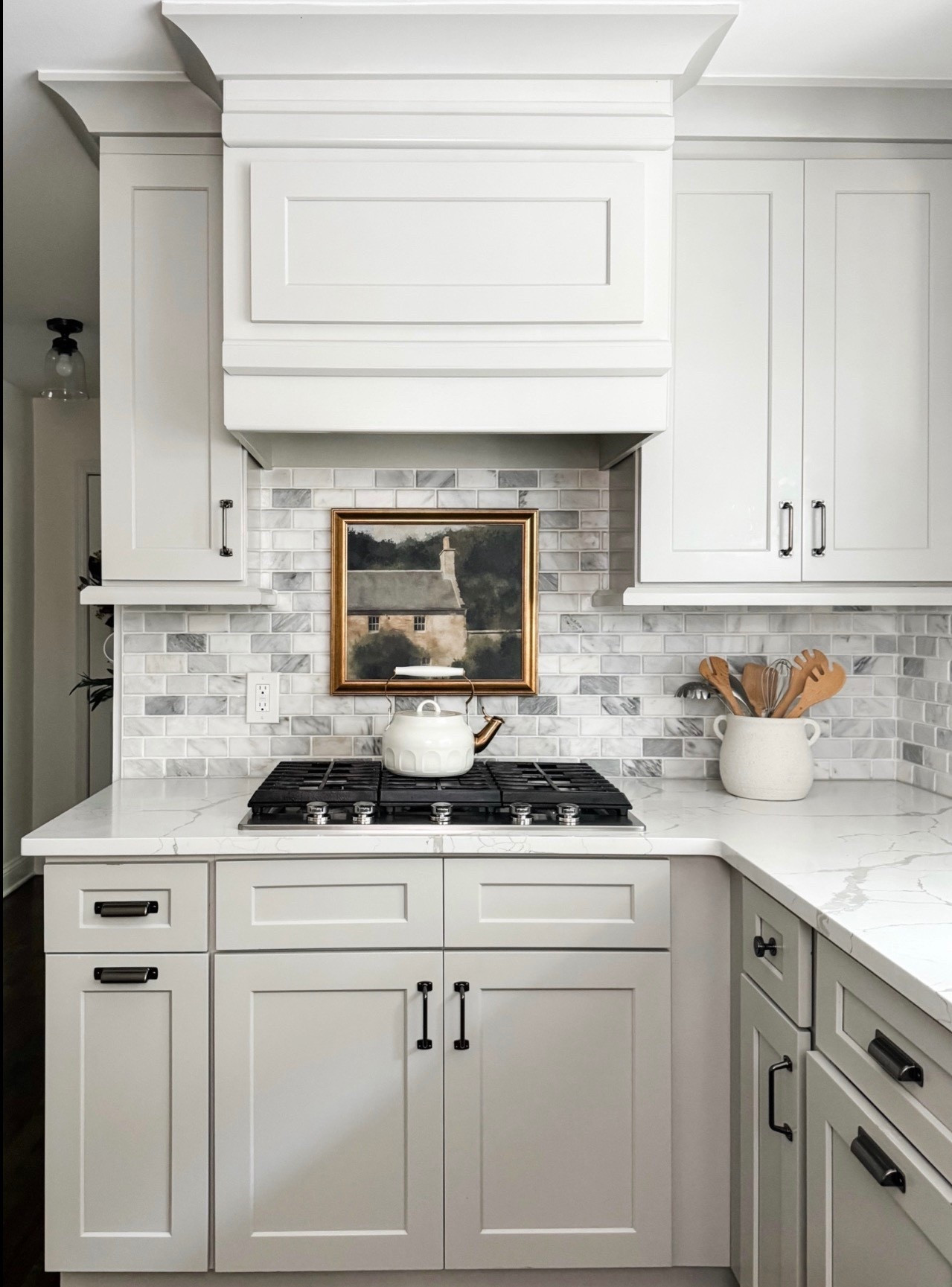 Classic white kitchen design with timeless details 🤍 This space features shaker style cabinets, a statement custom range hood, and a soft marble subway tile backsplash that adds texture without overpowering the room. The quartz countertops, gas cooktop, and matte black cabinet hardware bring a clean, modern contrast, while the framed artwork, ceramic utensil crock, and wood cooking utensils add warmth and charm. A perfect blend of traditional kitchen style and modern functionality.

#eanesinteriors #whitekitchen #kitchendesign #shakercabinets #customrangehood #marblebacksplash #subwaytile #quartzcountertops #gascooktop #kitchenhardware #blackhardware #kitcheninspo #classicinteriors #ltkhomestyle

#LTKHome #LTKdayinmylife #LTKSeasonal