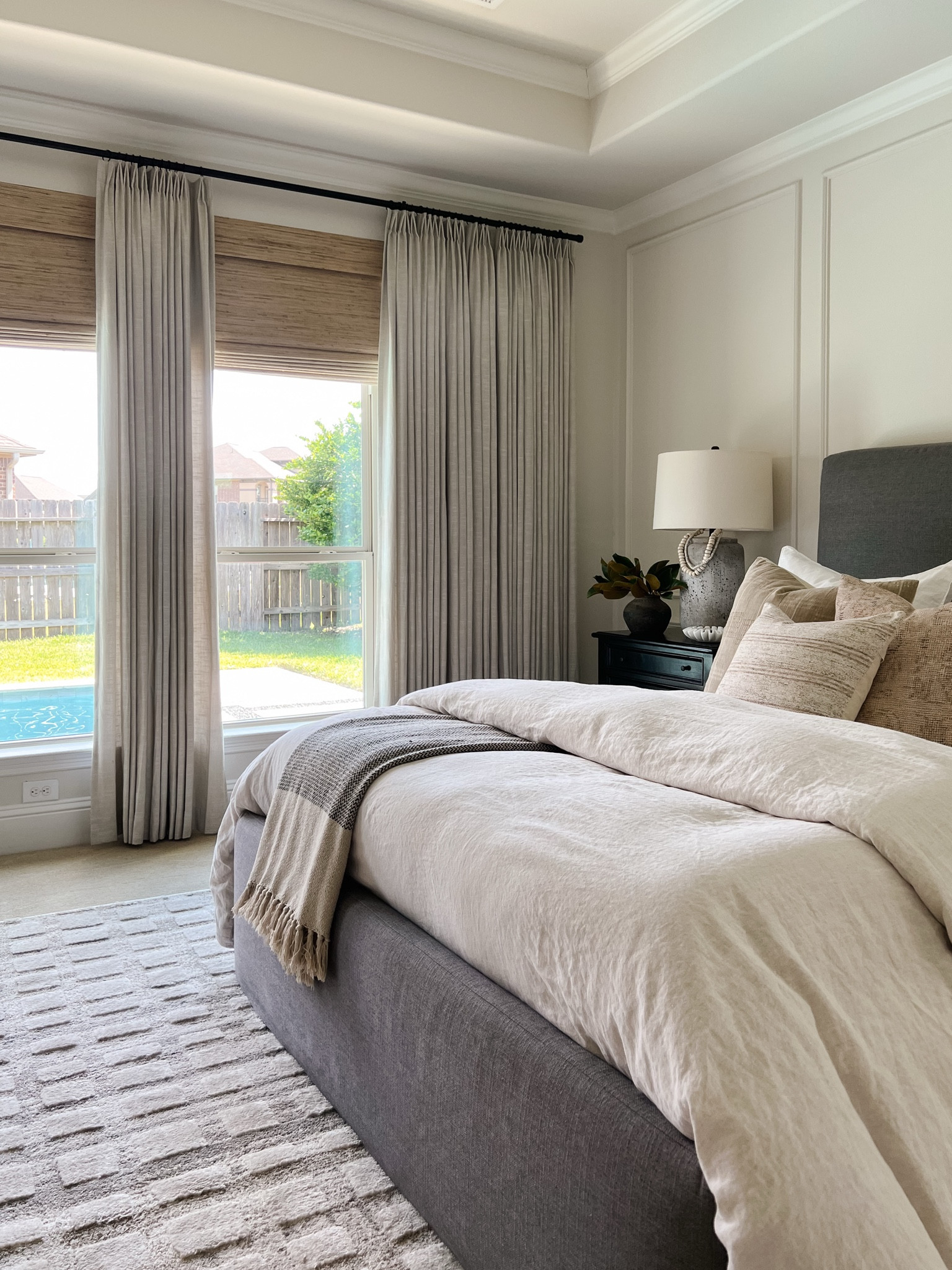 My neutral bedroom with linen drapes, natural shades, DIY grey upholstered bed, linen duvet, black nightstand, and textured rug



#LTKHome