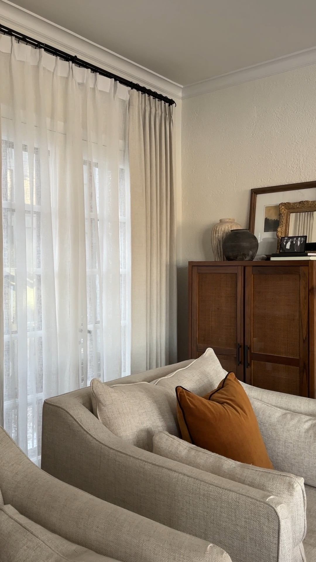 living room corner details *rattan cabinet, earth tone vase, camel colored pillows, sheer curtains, pleated curtains, double rod  