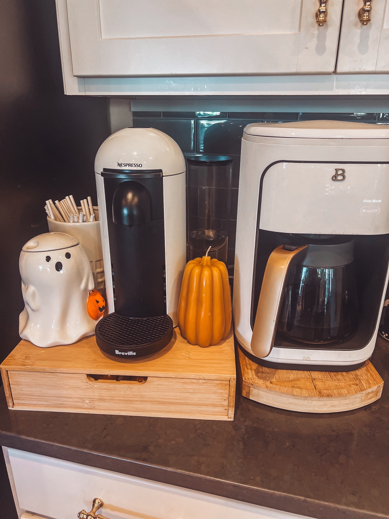 Halloween coffee bar 
White nespresso maker
White and gold coffee maker 
Bamboo coffee maker slider and stand with drawers 
Pumpkin candle 
 