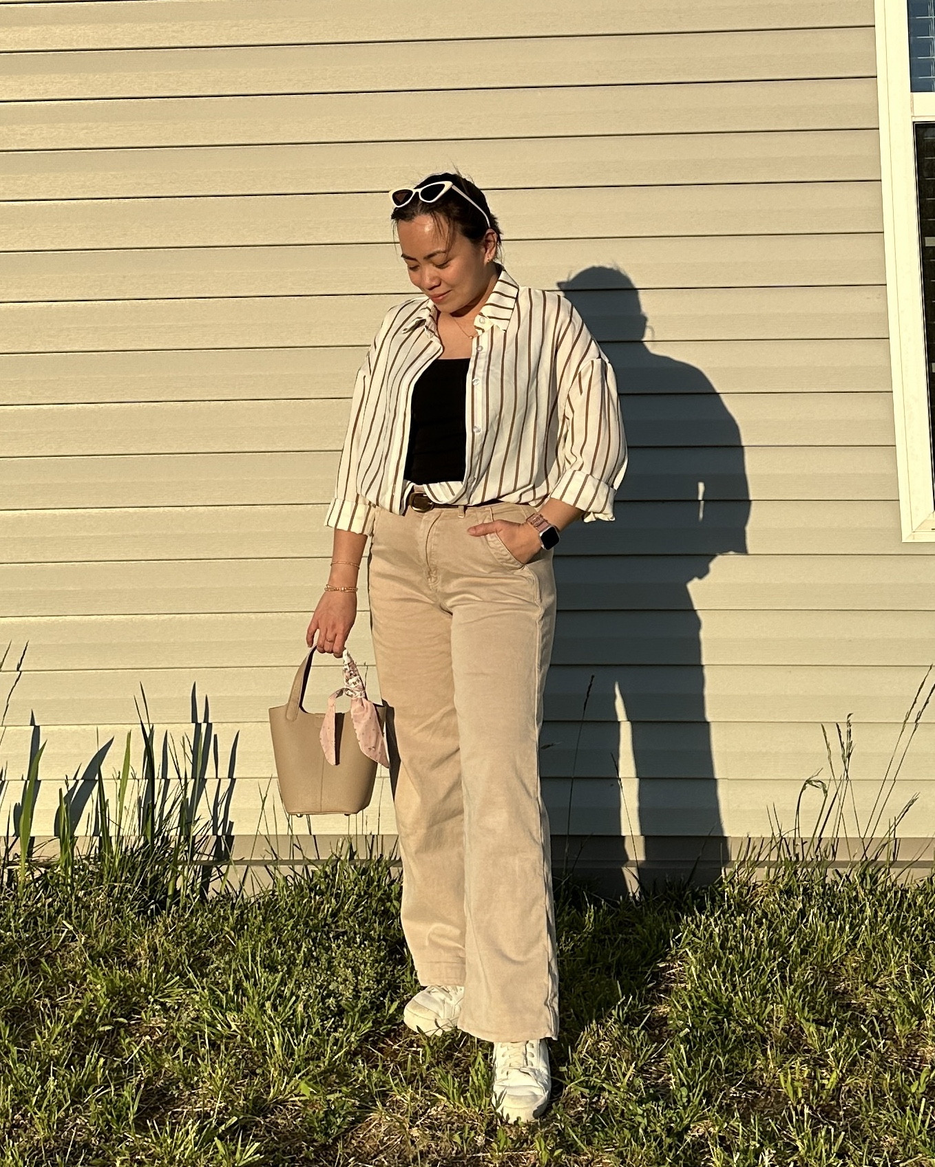 Effortless mom style: Cream wide-leg jeans, paired with a chic black sleeveless top layered with a striped button-up shirt, cinched with a brown belt, and finished off with crisp white sneakers.

#LTKstyletip