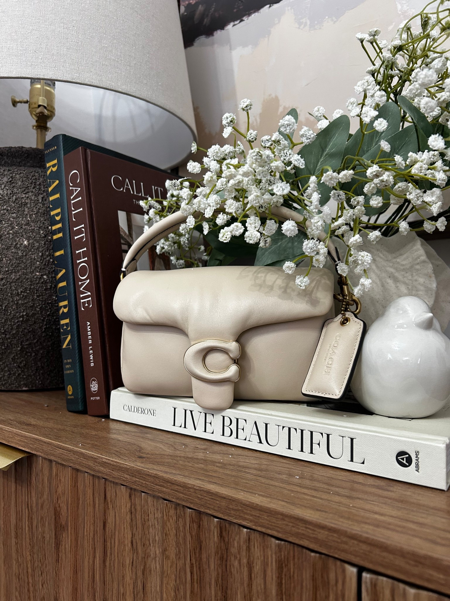 Soft neutrals, cozy textures, and a little touch of luxe 🤍✨
Styling moments like this just makes home feel extra calm and elevated. The mix of warm wood, stacked coffee table books, and fresh florals = effortless beauty.

Bag of the day: my Coach Pillow Tabby 18 in the dreamiest neutral… she fits right in 🤍

This is your reminder that the little corners matter 🌿

#homedecor #cozystyling #neutralhome #interiorinspo #shelfstyling #coachbag #luxeliving

#LTKSeasonal #LTKstorytime #LTKHome