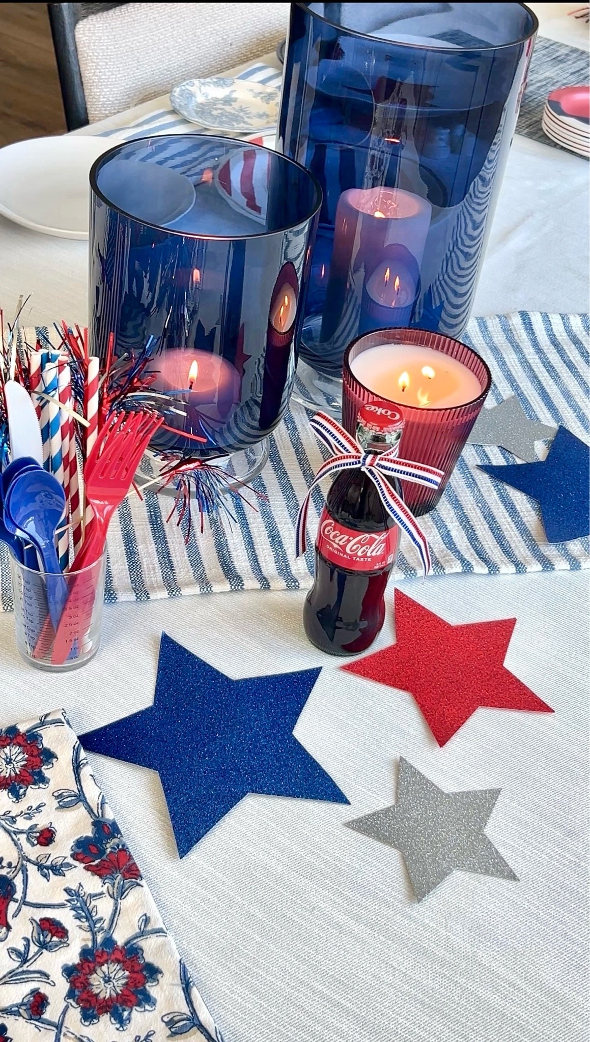 Everyday dishes styled for a patriotic tablescape using neutral white dinner plates, blue floral toile salad plates, woven rattan chargers, striped linen napkins, star print napkins, red white and blue ribbon bow detail, mini Coca-Cola glass bottles, summer hosting table, 4th of July table decor, Memorial Day table, Americana table setting, layered place settings, casual elegant entertaining, hostess styling ideas, mix and match dishes, budget friendly tablescape, outdoor summer dining inspiration, modern classic table styling

#LTKHome #LTKSeasonal
