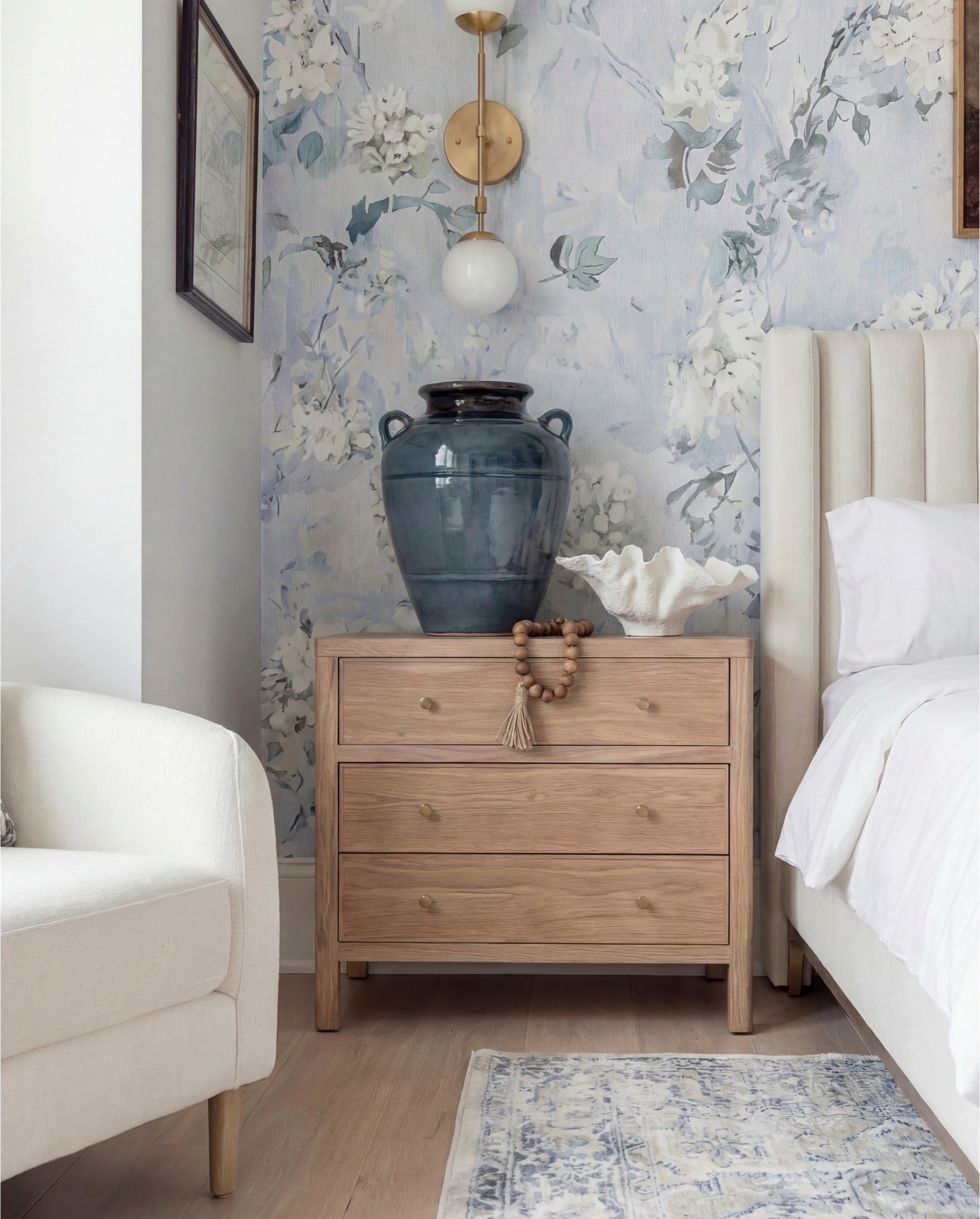 Shop the Look: Bedroom Refresh
This bedroom feels soft, romantic, and effortlessly refined. The airy blue floral wallpaper sets a calm, classic tone, while warm wood beams and brass accents bring balance and depth. The upholstered bed anchors the space with clean lines, layered with crisp white bedding and blue accent pillows that echo the wallcovering. Natural wood nightstands and ceramic decor add warmth, while the styling stays light, timeless, and collected.

The details elevate it—globe lighting, sculptural ceramics, and subtle texture from rugs and throws create a space that feels serene but thoughtfully finished.

Shop the Look:
• Blue floral wallpaper (soft watercolor style)
• Exposed wood ceiling beams
• White globe pendant light with brass chain
• Brass wall sconces with globe shades
• Upholstered bed frame (ivory fabric)
• White duvet + sheet set
• Blue patterned accent pillows
• Solid neutral throw pillows
• Wood nightstands (light oak tone)
• Blue ceramic urn-style vase
• White sculptural ceramic bowl
• Wooden bead garland with tassel
• Framed floral artwork above bed
• Upholstered bench at foot of bed (cream)
• Patterned area rug (blue and ivory tones)
• Knit throw blanket (warm neutral)

#LTKHome #LTKSaleAlert